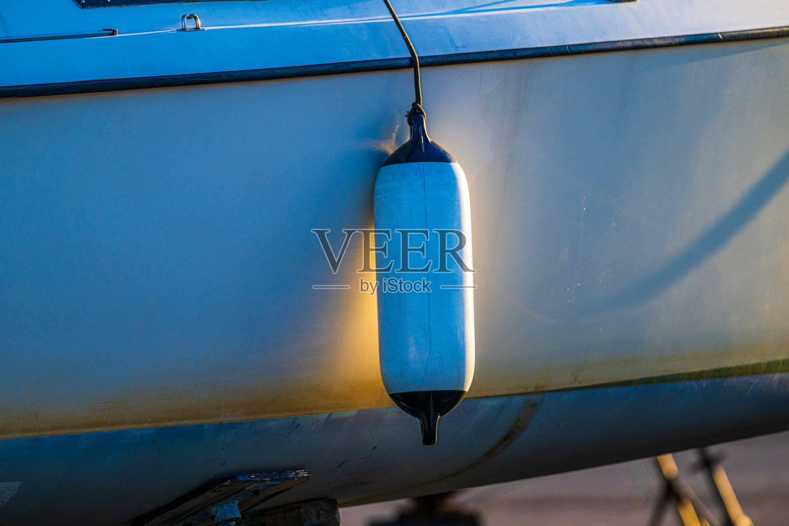 船用护舷在日落时挂在船体上。照片摄影图片