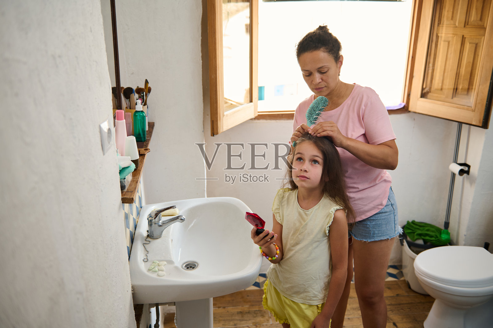 母亲在温馨的浴室里为女儿梳头发照片摄影图片