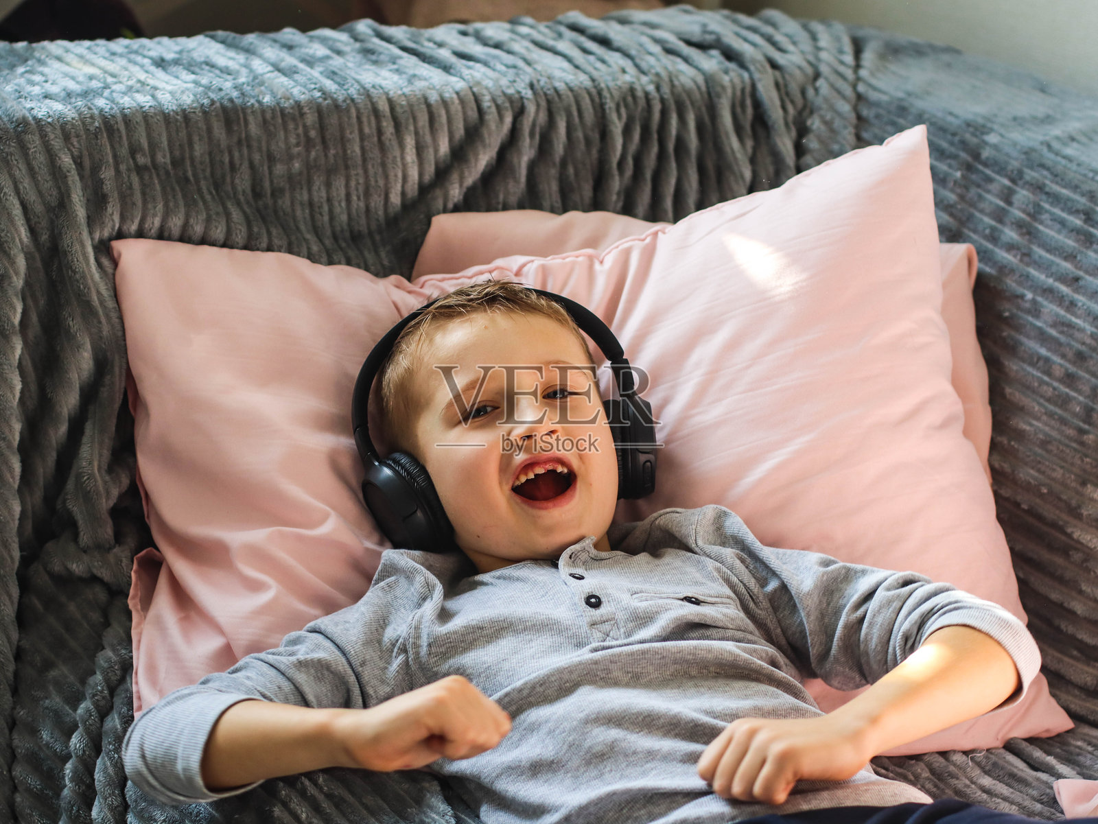 男孩坐在房间的沙发上戴着耳机听音乐照片摄影图片