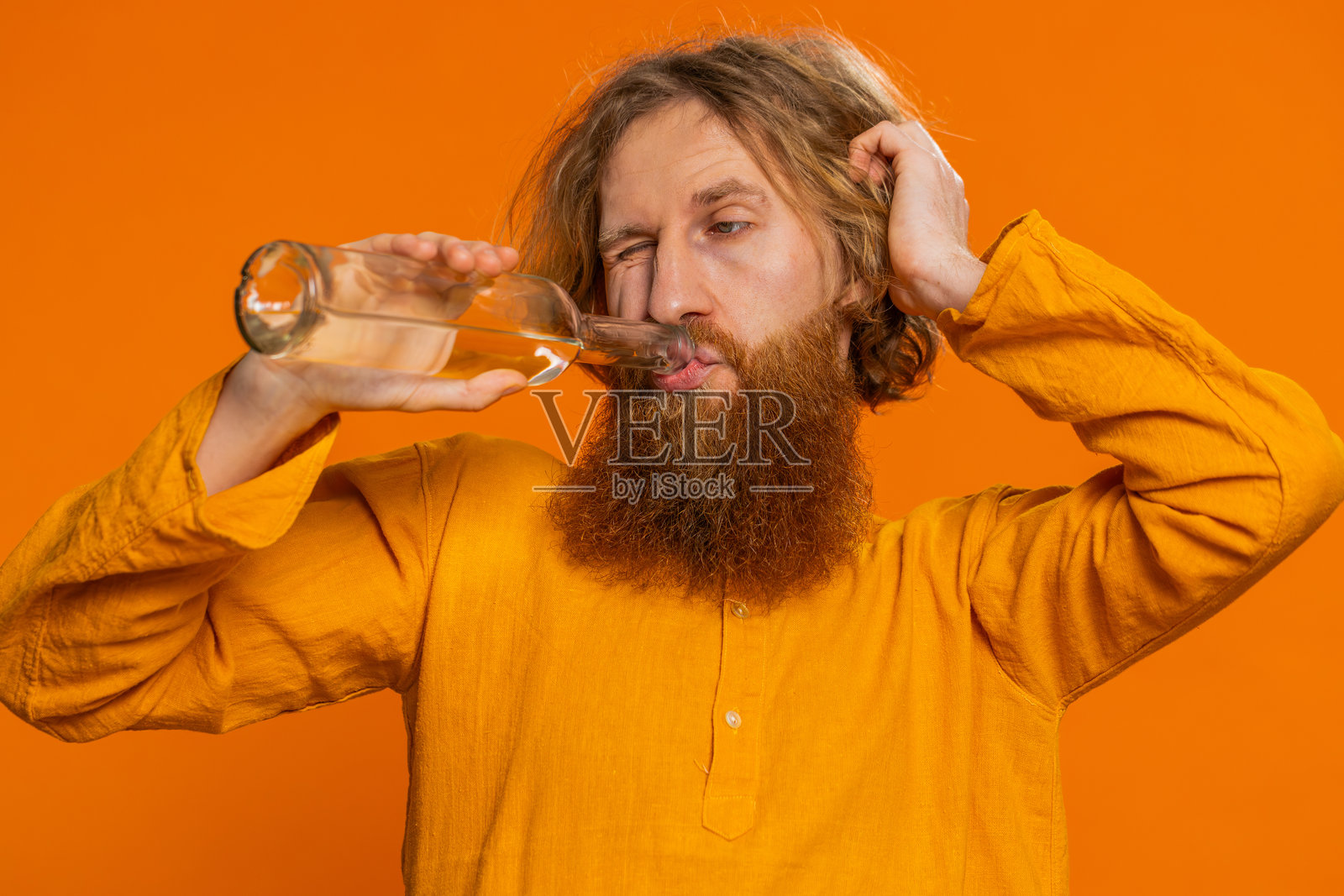 醉酒的白人男子在派对后从瓶子里喝伏特加,庆祝战胜成瘾的胜利。照片摄影图片