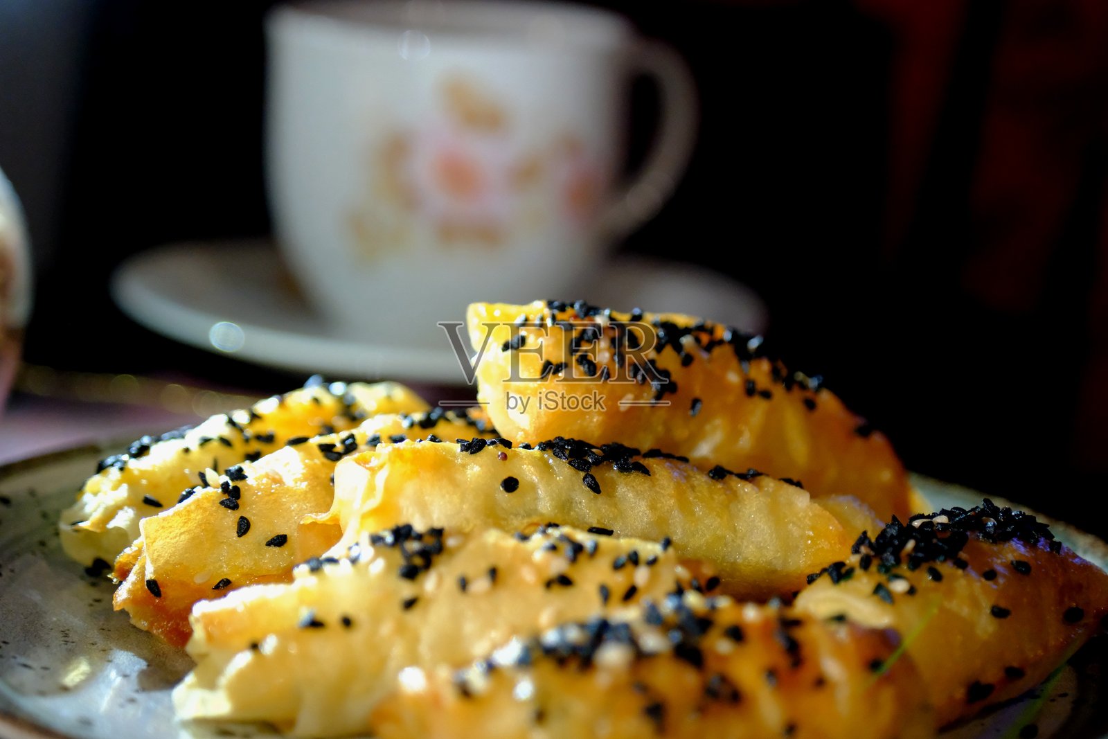 自制热小吃卷,外层为优夫卡酥皮,上面撒有奶酪、黑孜然和芝麻,特写展示。照片摄影图片