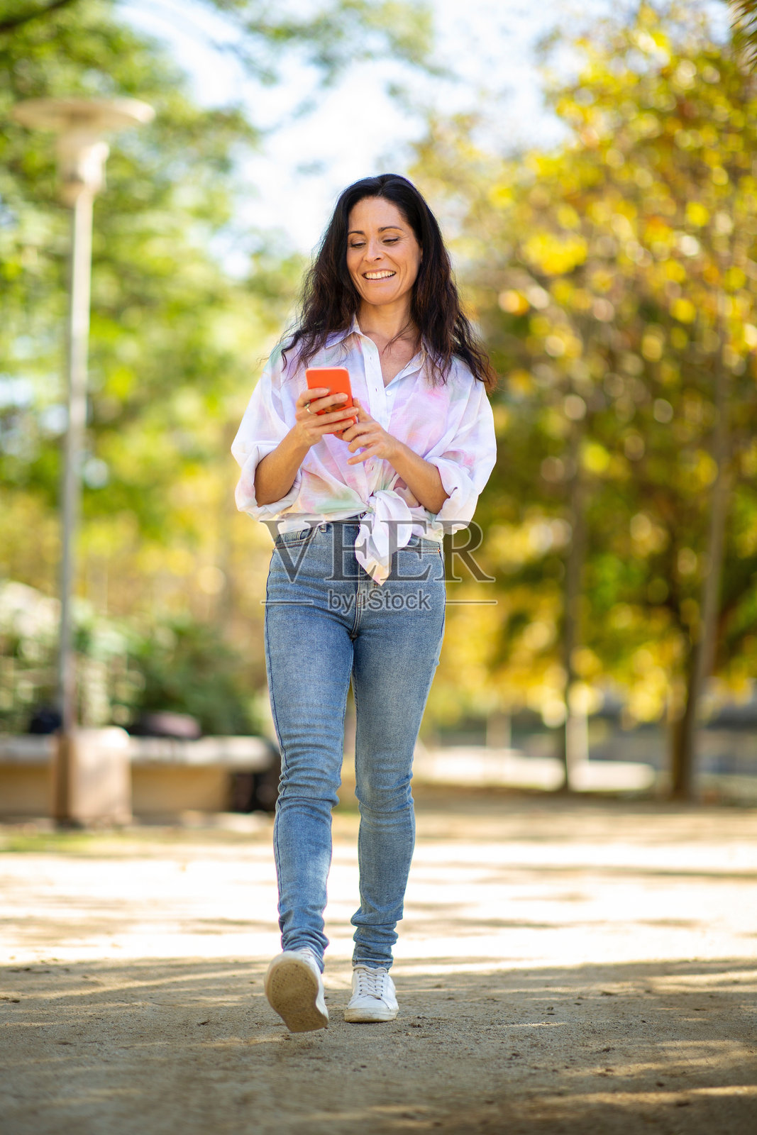 快乐的女人在公园户外使用手机照片摄影图片