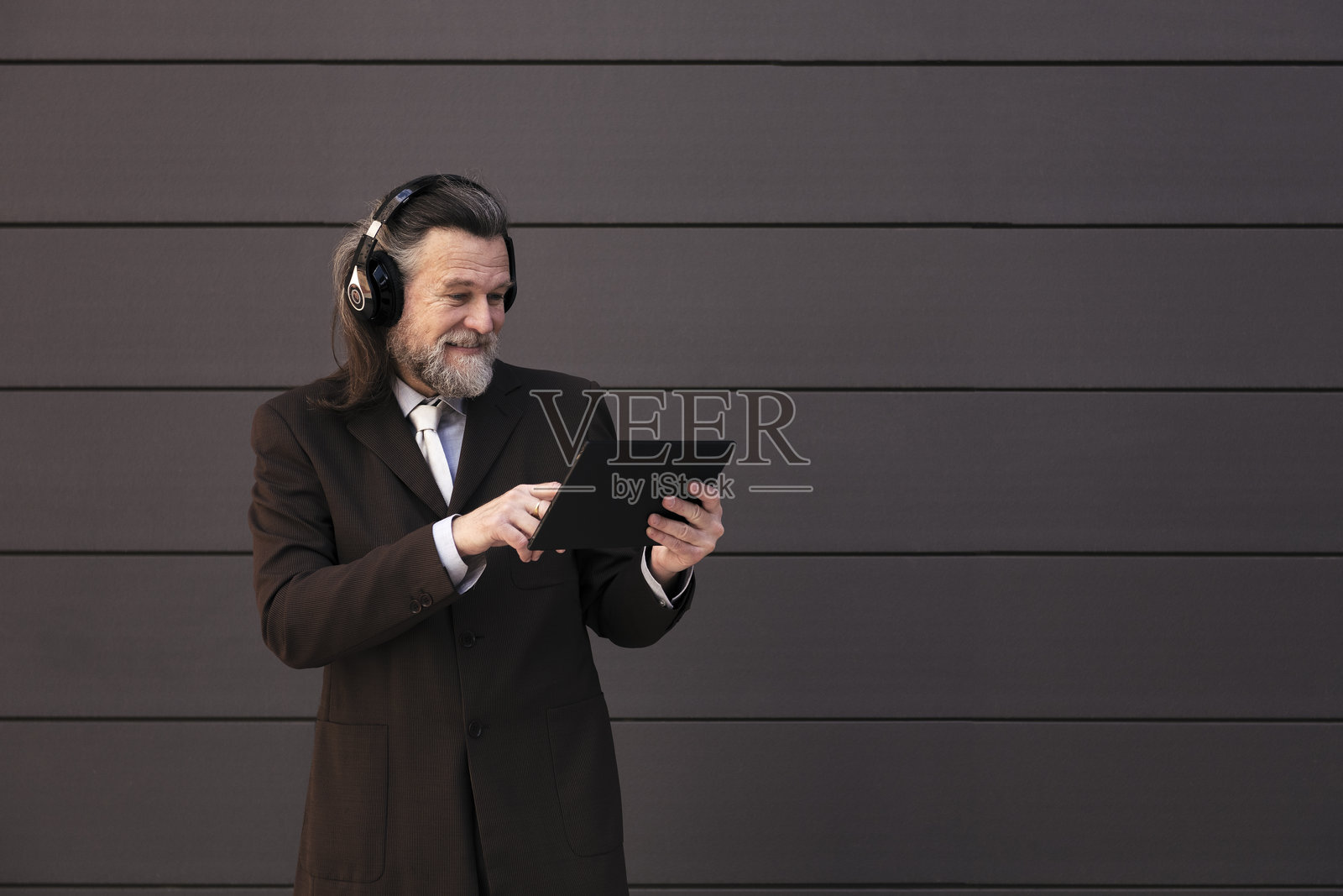 优雅的成熟男士使用平板电脑和耳机照片摄影图片