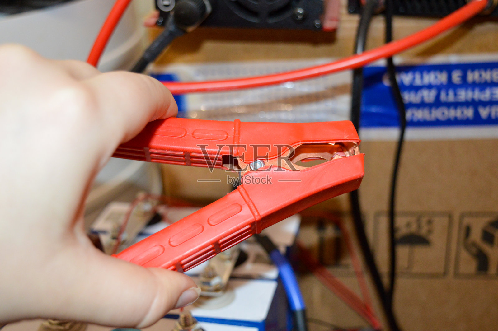 手握红色跳线夹的电池系统连接布线设置,技术电气环境,能源存储,汽车维修,离网电力解决方案,充电维护,可再生能源照片摄影图片