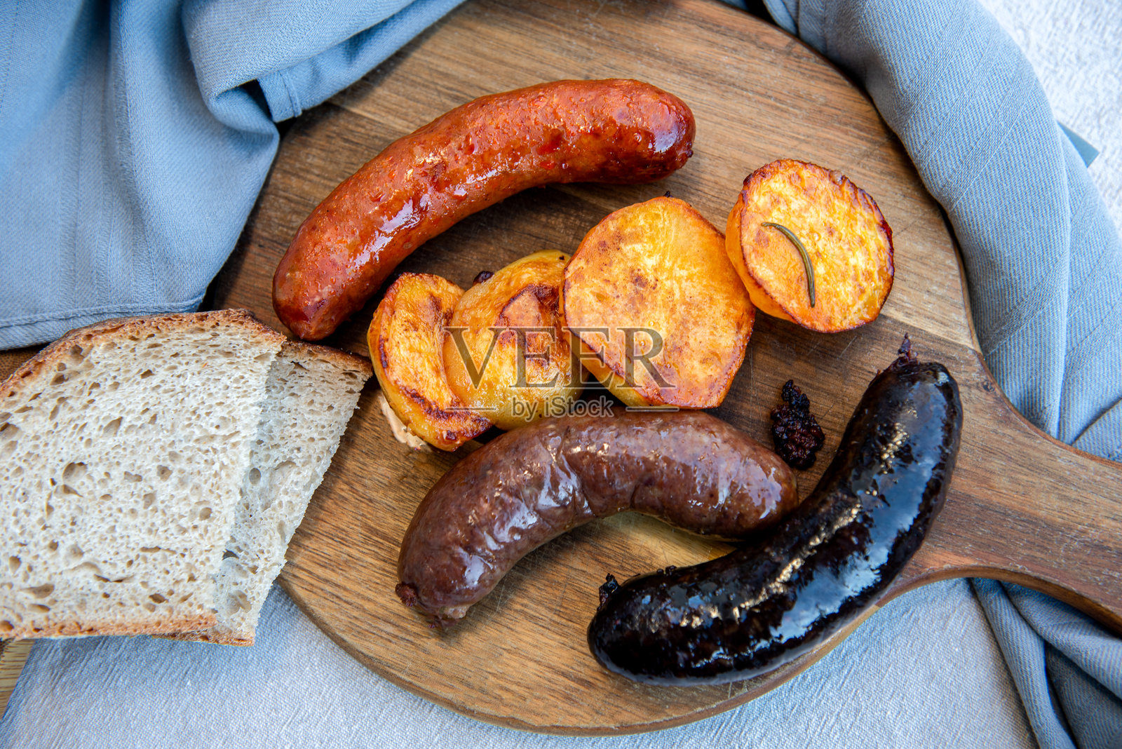 自制血肠、猪肉香肠和西班牙香肠的特写,搭配土豆,摆放在木板上,传统自制美食。照片摄影图片