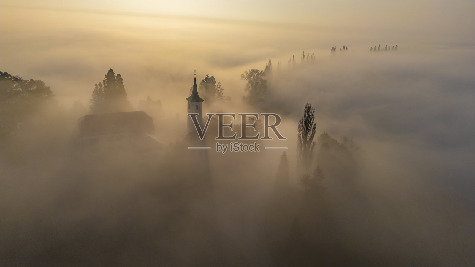 雄伟的教堂在日出时分穿透迷人的雾气照片摄影图片