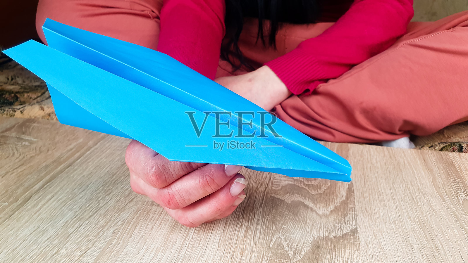 女孩坐着玩纸飞机。纸飞机,产品,手工艺,折纸。照片摄影图片