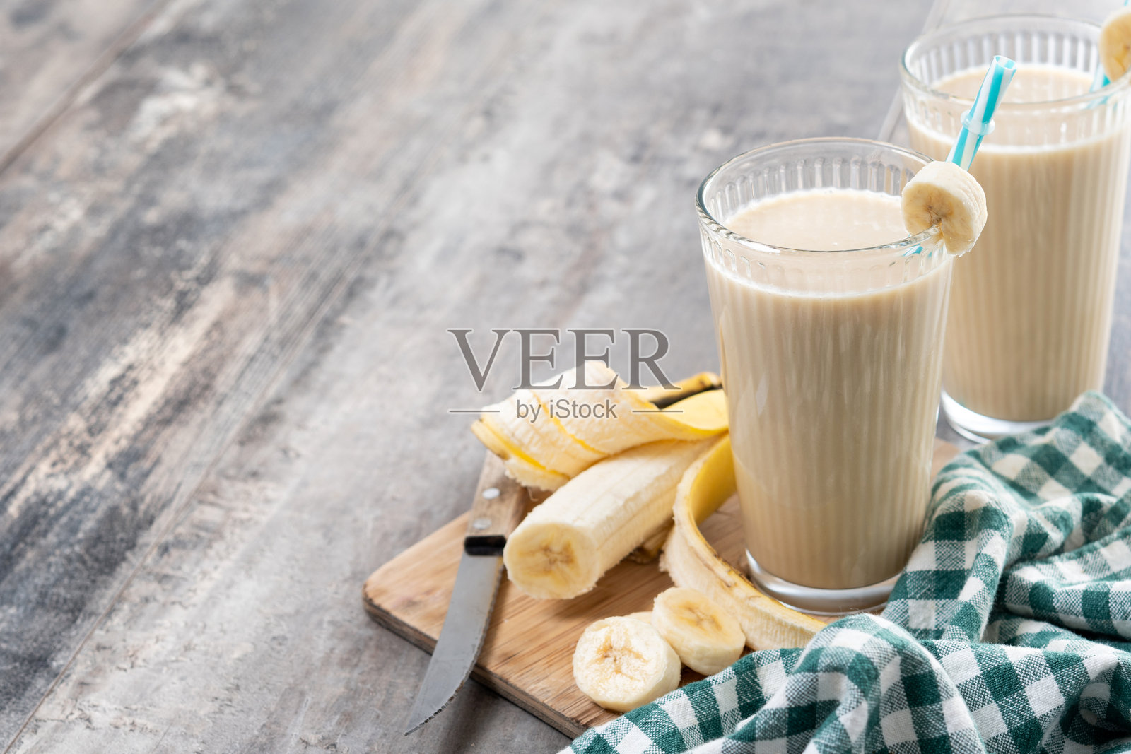 新鲜香蕉奶昔放在白色木桌上。照片摄影图片