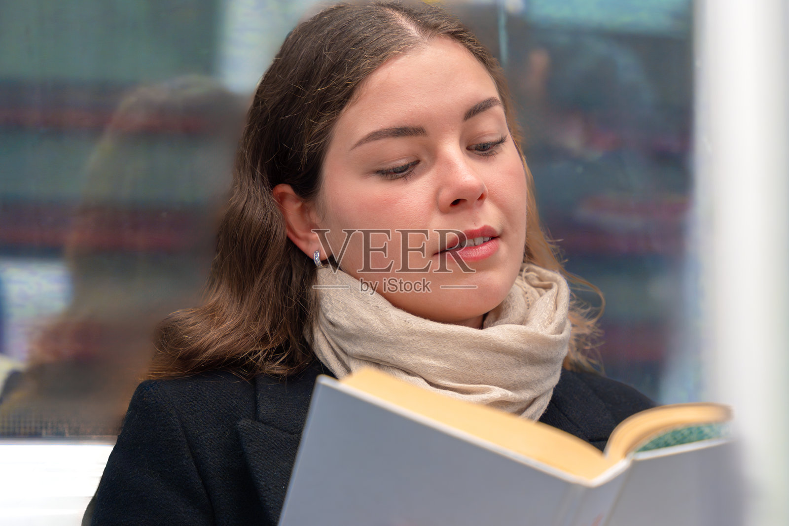 年轻女性在地铁上阅读一本书照片摄影图片