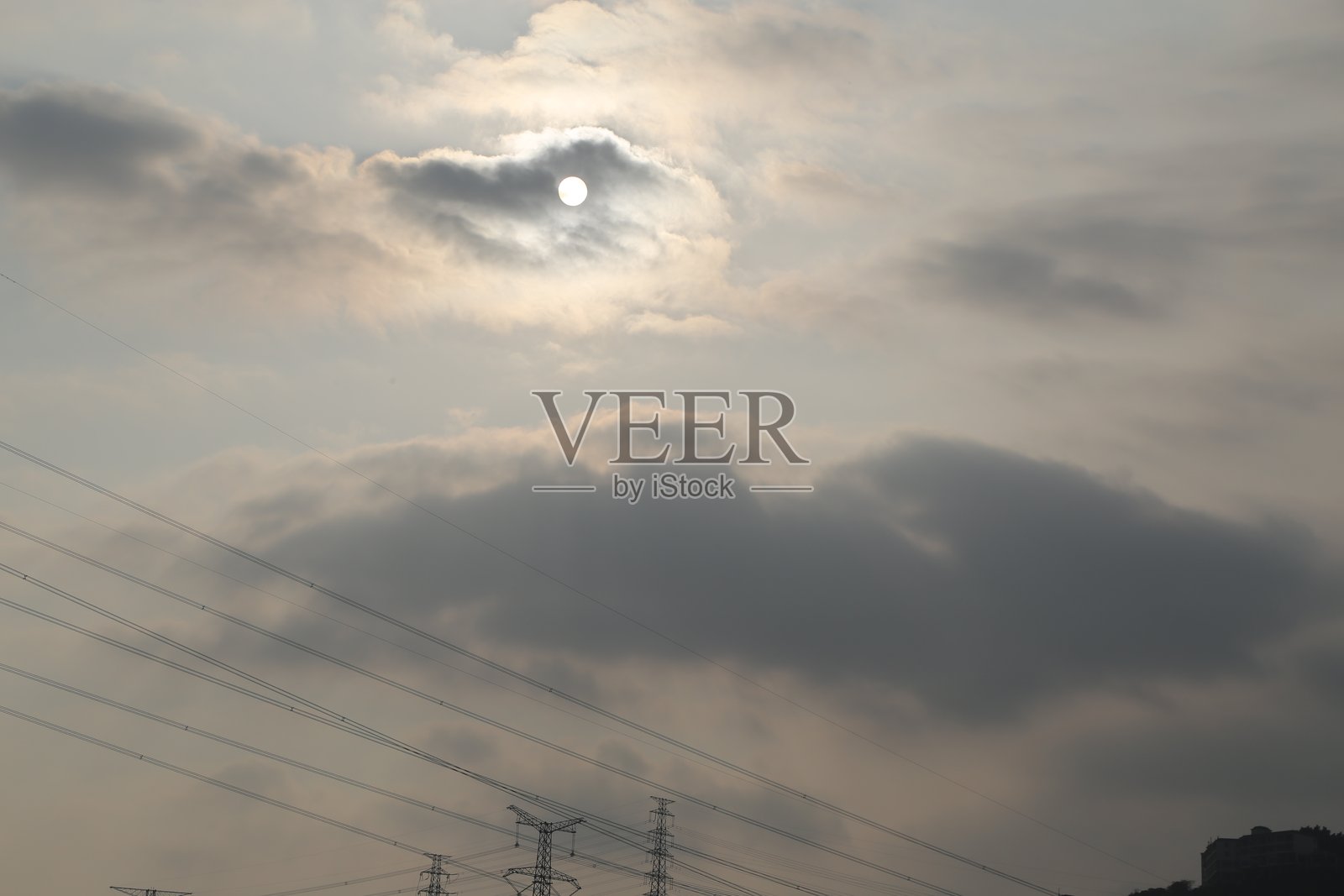 太阳被云层遮住,一些电线穿过云层。照片摄影图片