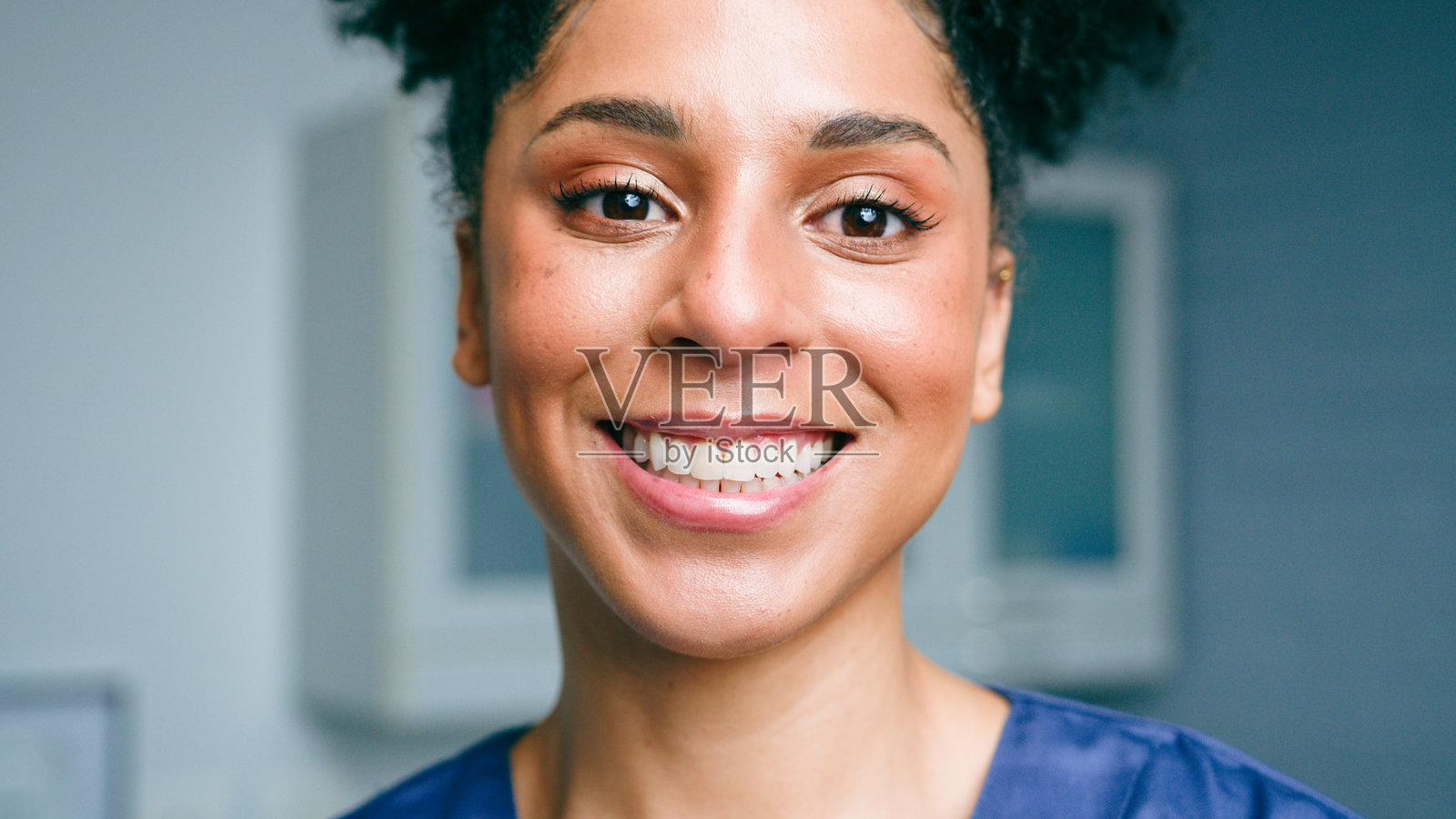 微笑的牙科专业人士穿着护士服,身处现代诊所环境中照片摄影图片