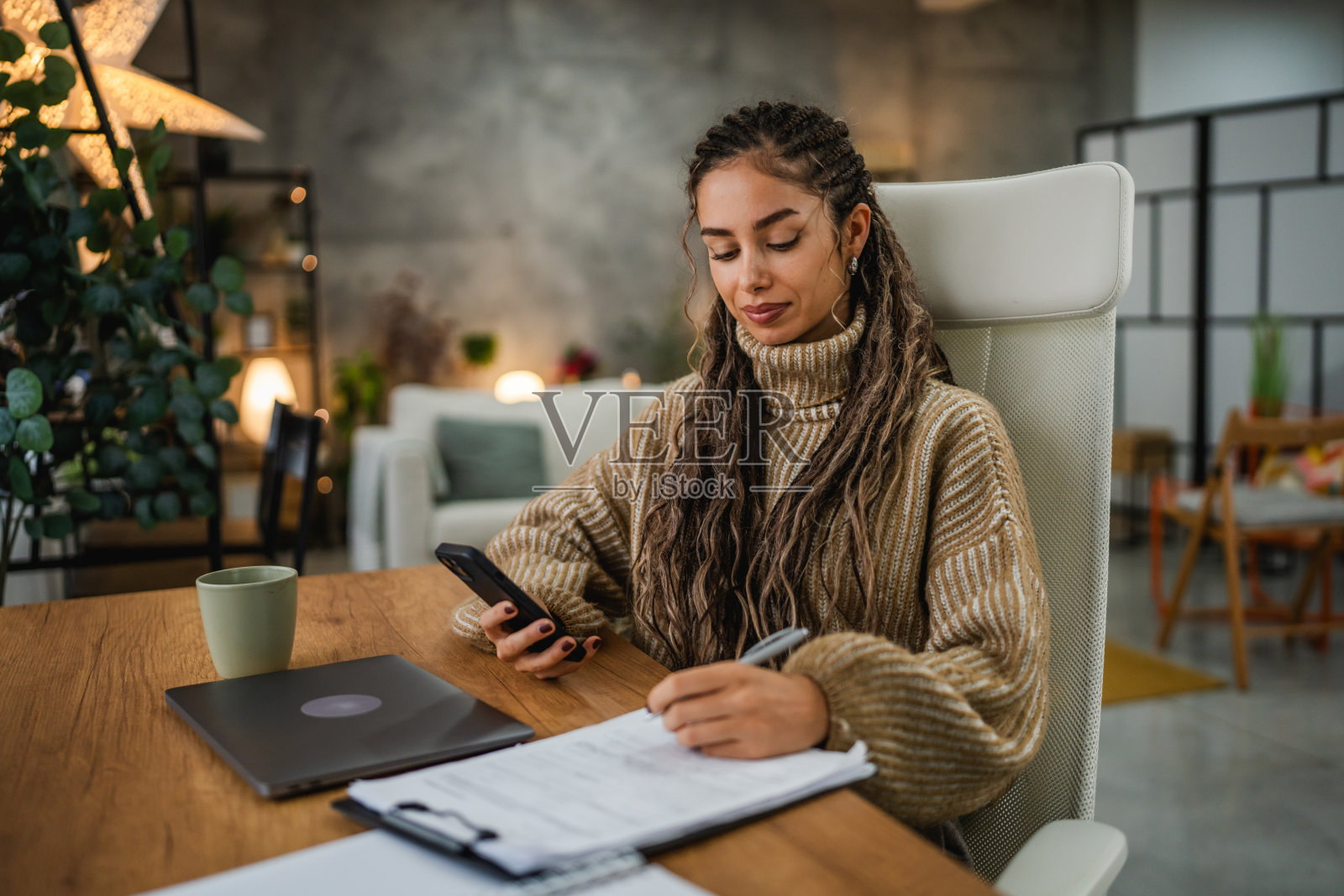 年轻女性在家办公,使用夹板和手机工作照片摄影图片