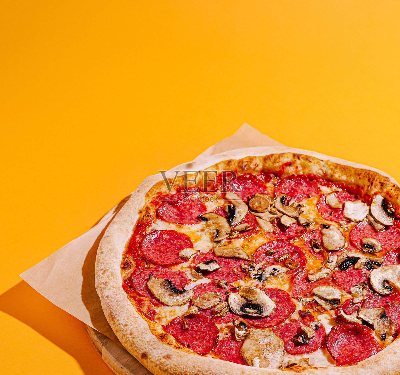 美味的披萨,上面放有意大利香肠和蘑菇,背景为鲜艳的橙色。照片摄影图片