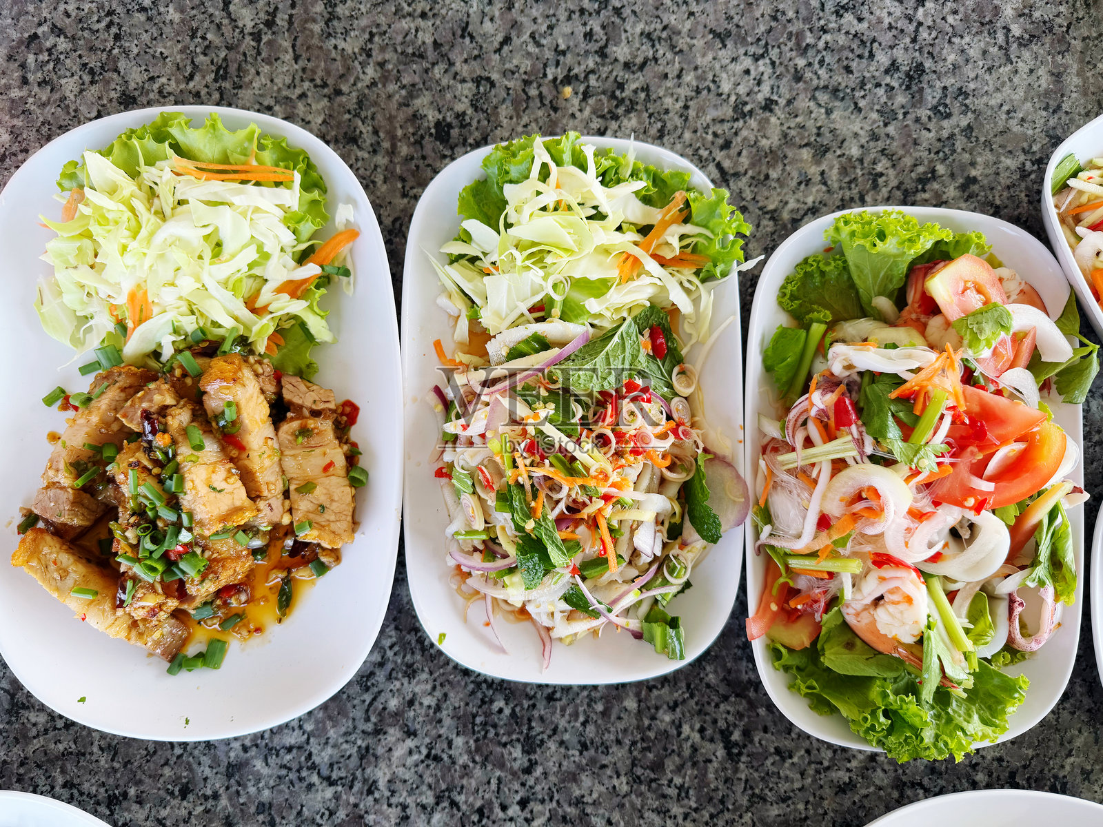 白盘子里的泰式辣味猪肉蔬菜沙拉放在桌子上照片摄影图片