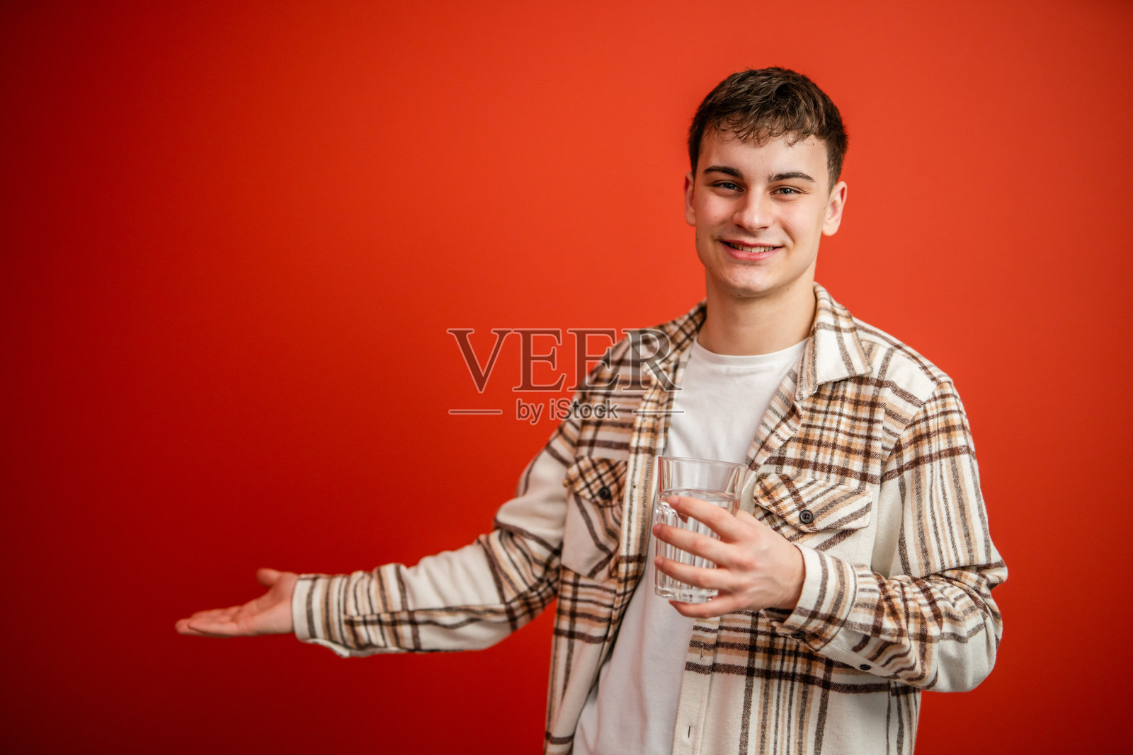 年轻男子在红色背景前喝水的肖像摄影照片摄影图片