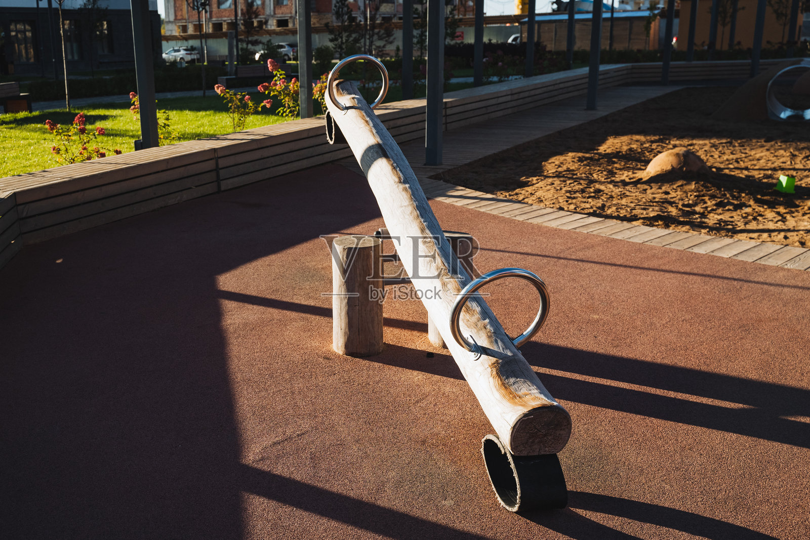 在一个美丽的公园里,一座木制的秋千静静地安放在地面上,周围环绕着生机勃勃的绿意和各种自然元素。照片摄影图片