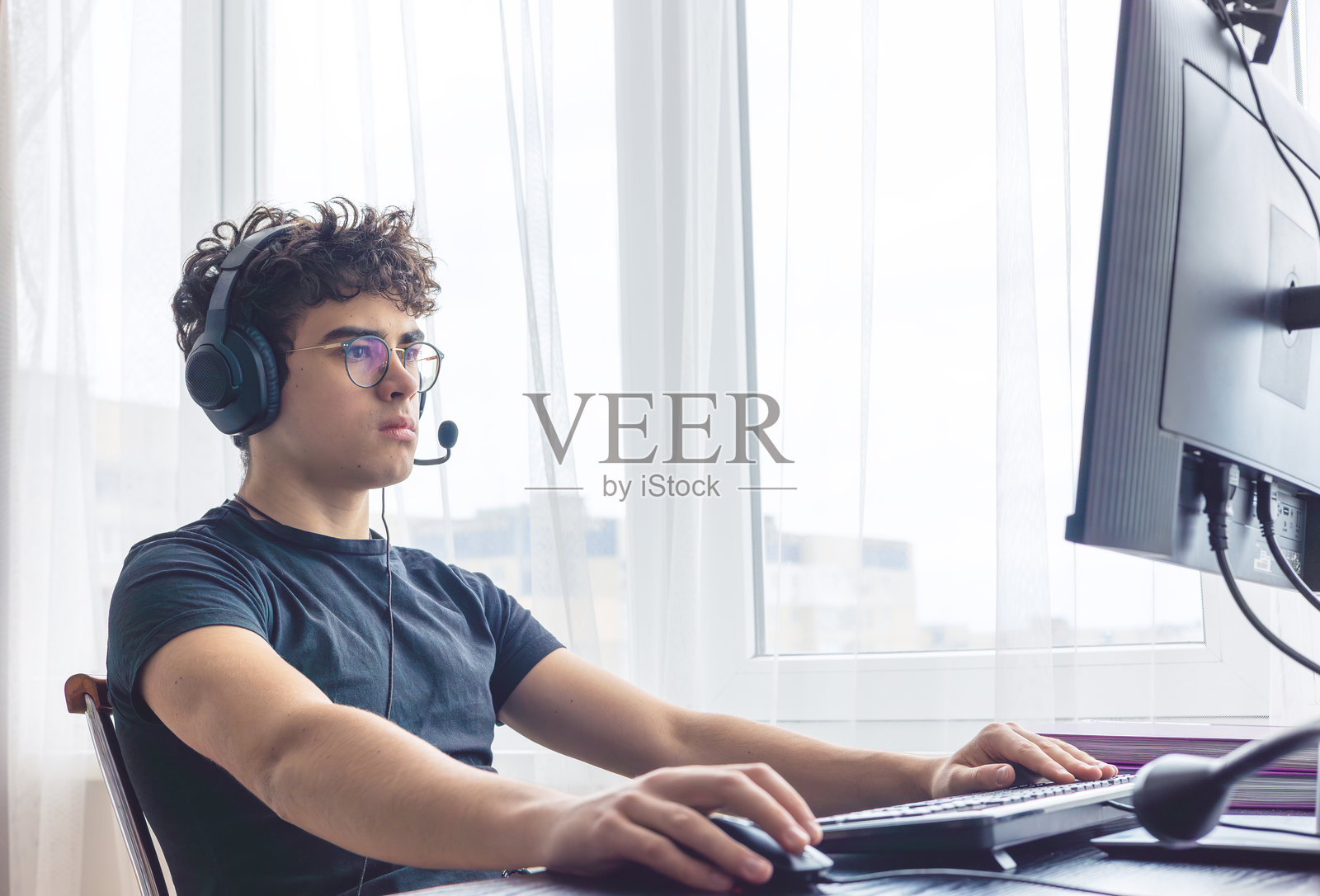 青少年电子竞技选手专注于游戏。青少年利用科技进行学习和游戏。青少年玩家在电脑上游戏。在家在线学习。在家用电脑学习数学。留白空间。照片摄影图片