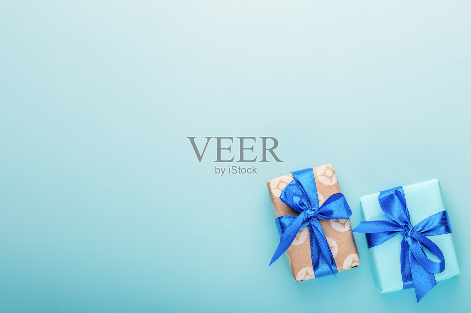 浅蓝色背景上的蓝色缎带礼品盒。节日礼物。照片摄影图片