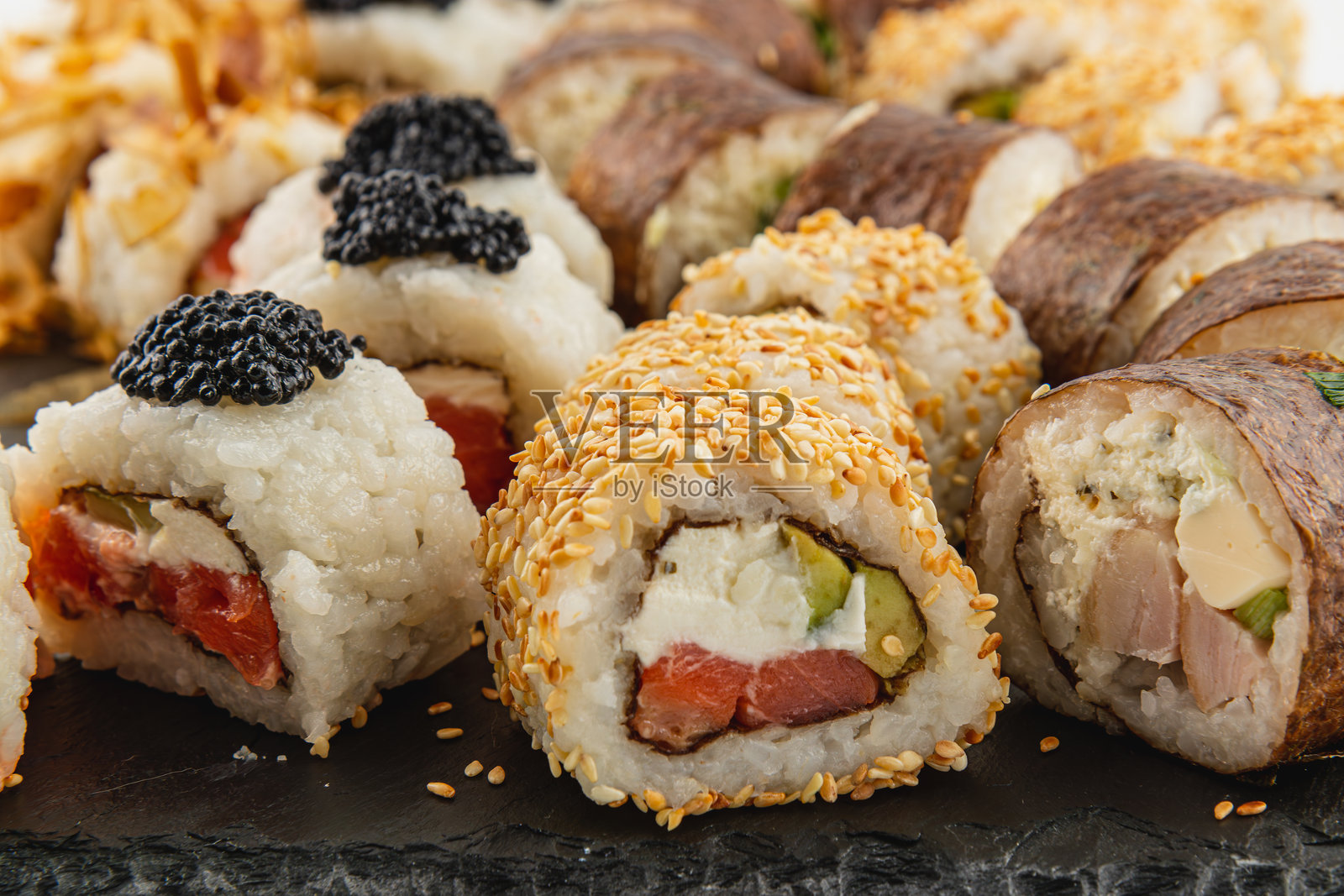 美味的寿司卷,配有多种馅料,盛放在黑色石板上照片摄影图片