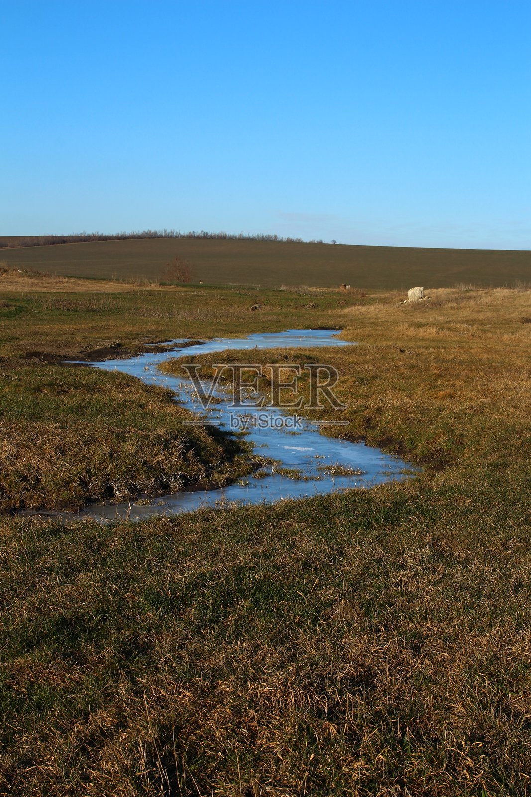 一片草地上有一条河流穿过照片摄影图片
