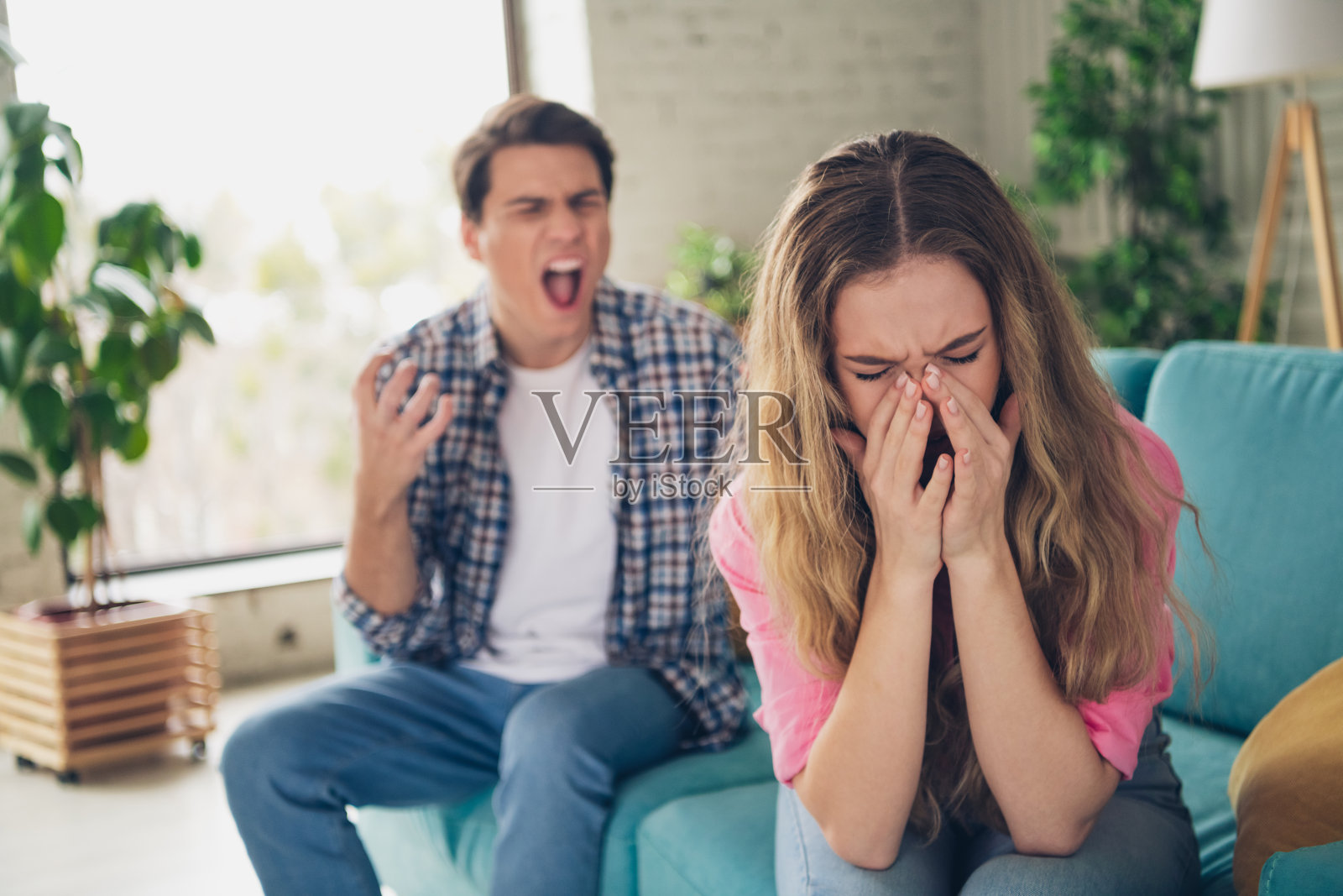 年轻情侣在现代客厅中感受情感压力,阳光透过窗户洒入。照片摄影图片