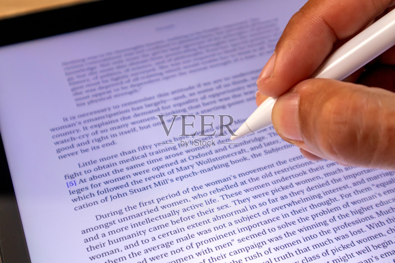 手握触控笔在平板上阅读电子书或期刊。无纸化。照片摄影图片