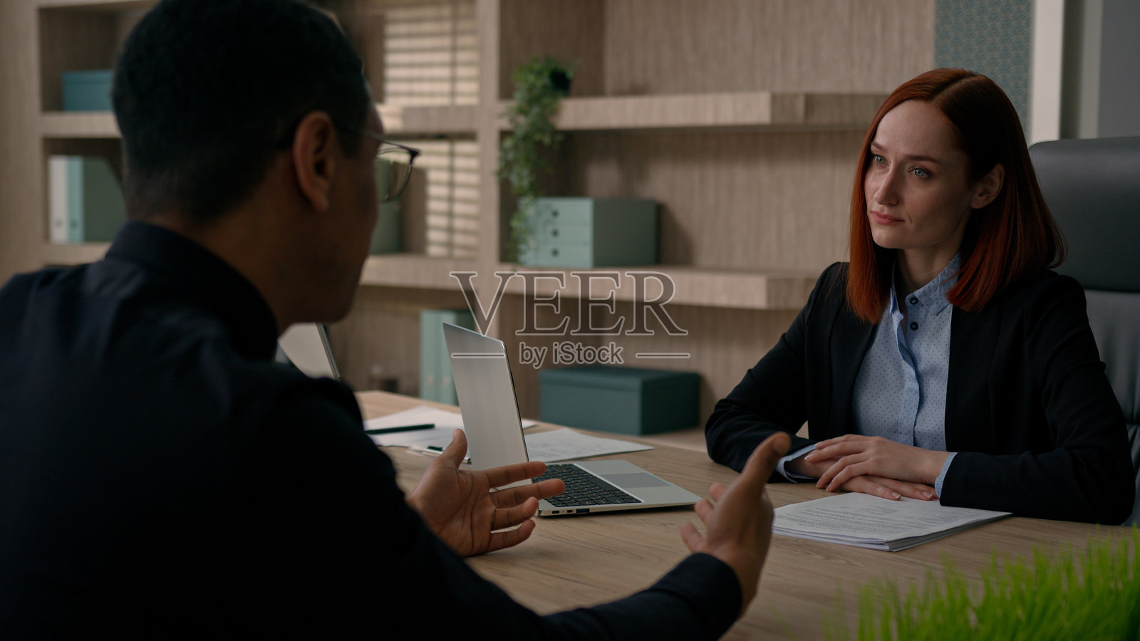 两位同事,跨种族的非裔美国男商人和白人女商人在办公室进行商业谈判,讨论初创企业的金融投资、银行和保险报价。照片摄影图片