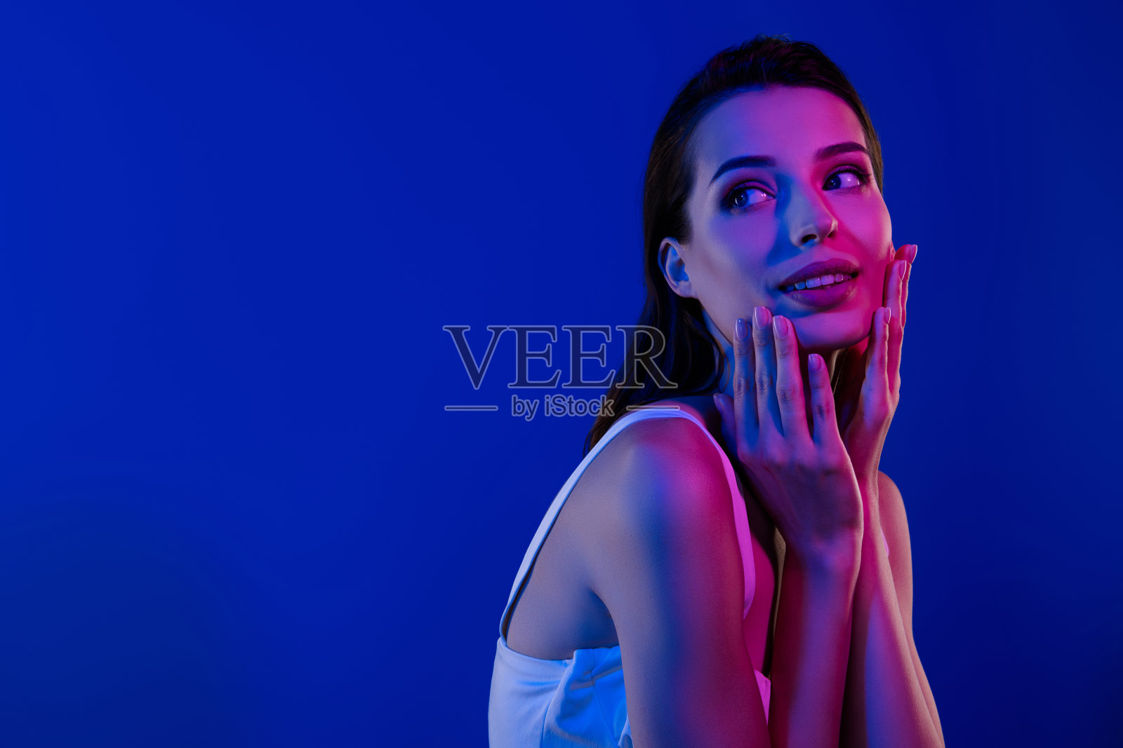 美丽迷人的女士在蓝色背景下享受经过疗程后的柔软、清新、完美的理想肌肤照片摄影图片