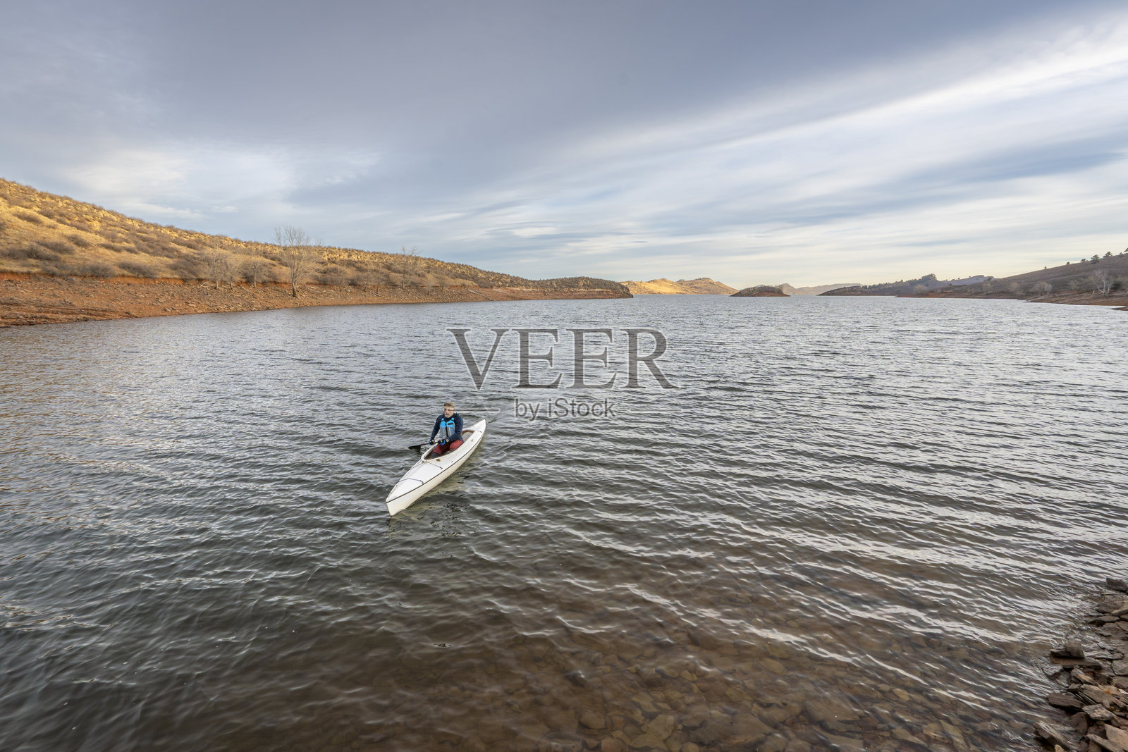 孤独的划艇者在洛基山脉脚下的霍斯图斯水库中进行探险,早冬的景色。照片摄影图片