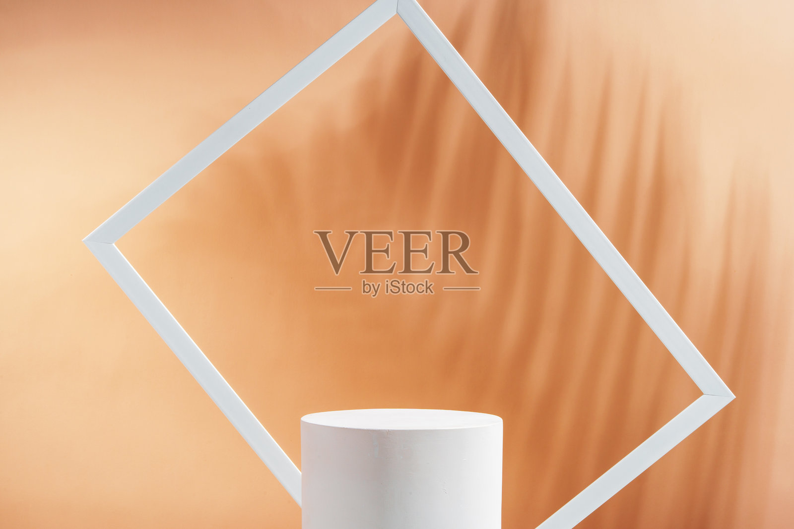 简约的白色圆柱形物体,框架为白色矩形边框,背景为柔和的橙色。照片摄影图片