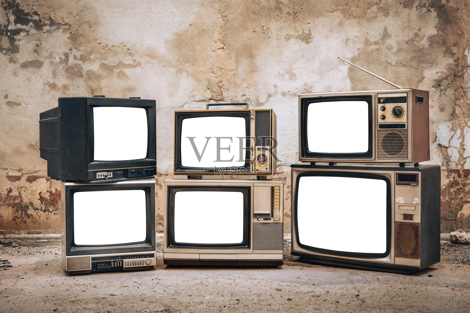 一堆复古旧电视机,屏幕被切割,放在老砖墙前的地板上,白色空白屏幕显示,旧电视机。照片摄影图片
