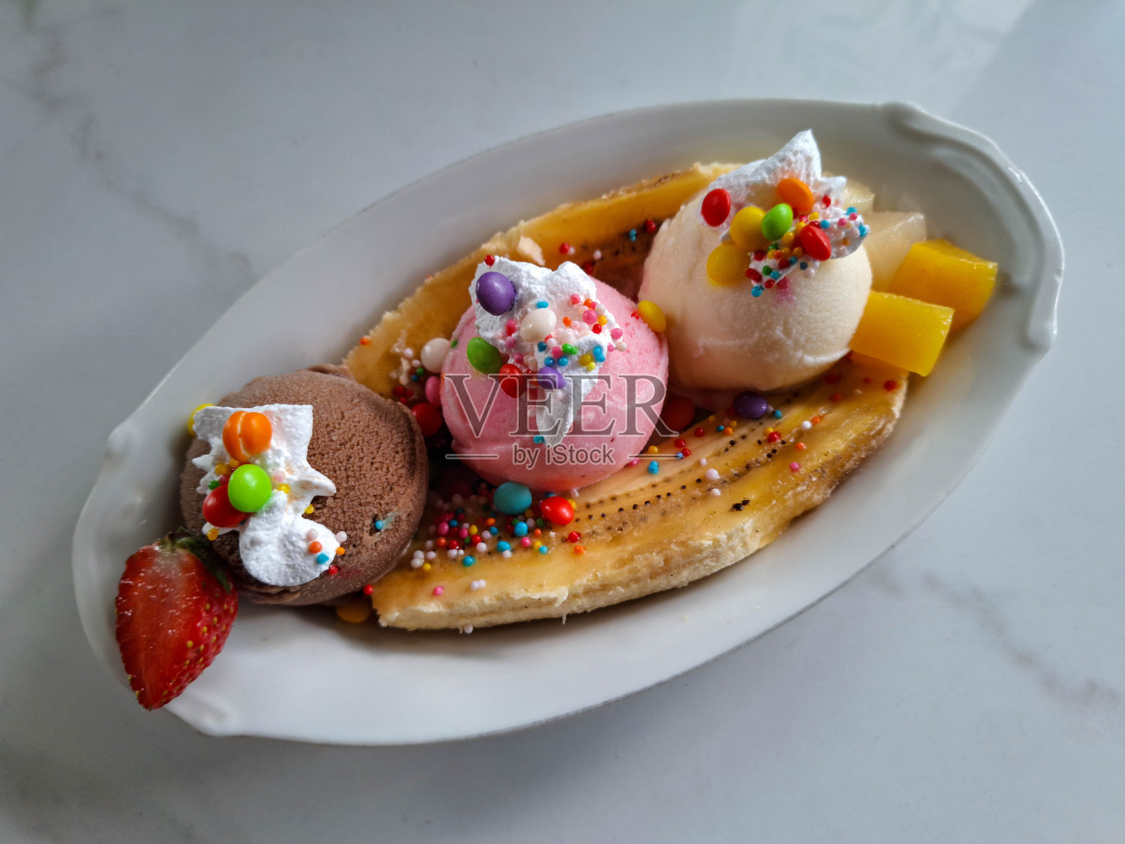 美味的香蕉船冰淇淋,配有香蕉、草莓、芒果、鲜奶油、糖果、巧克力冰淇淋、草莓冰淇淋和香草冰淇淋。甜点菜单。照片摄影图片