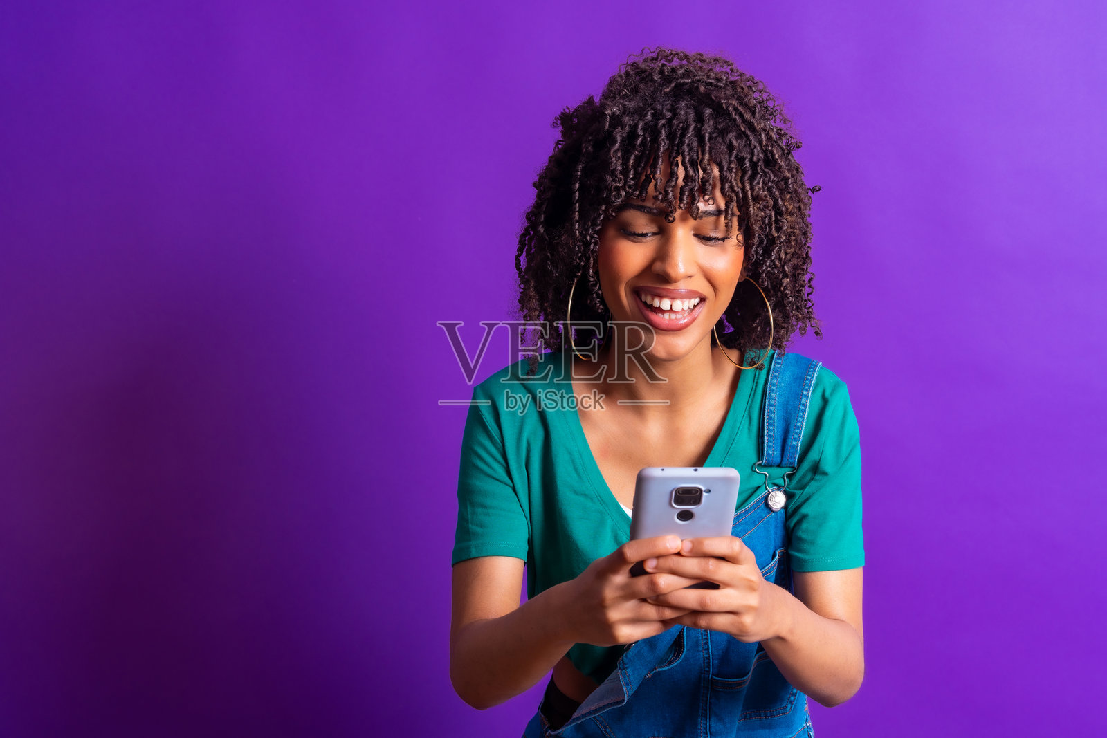 年轻女性在紫色背景下使用智能手机并微笑照片摄影图片