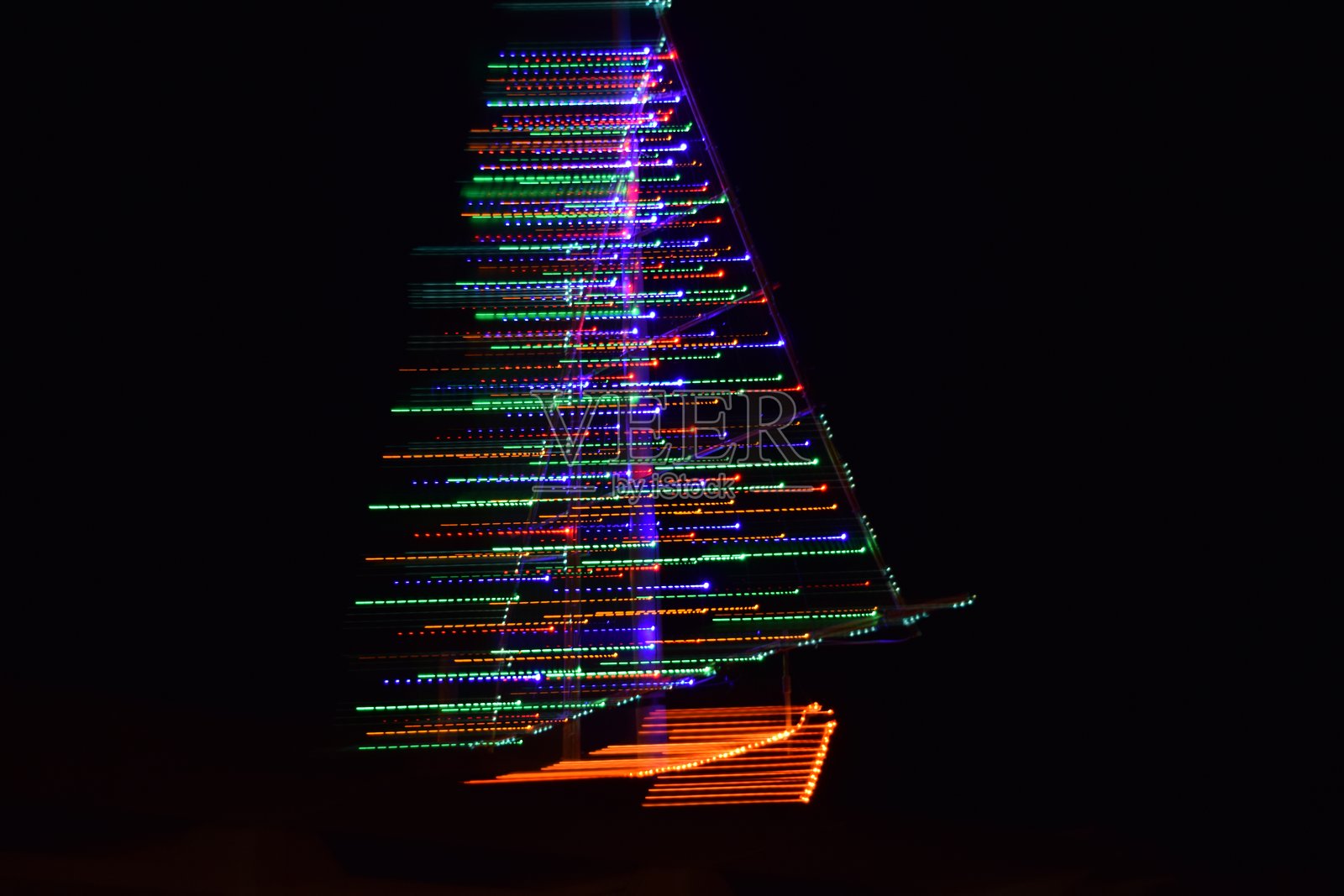 夜间拍摄的帆船,五光十色的灯光照亮。照片摄影图片