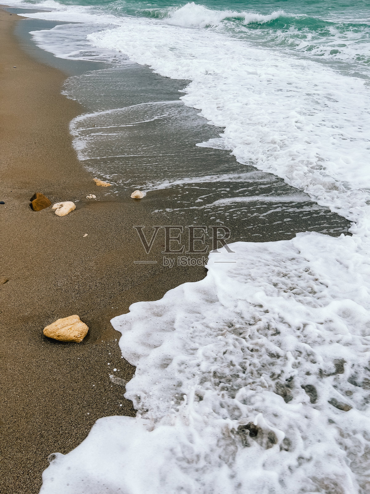 海浪拍打在沙滩上,形成白色泡沫。温柔的海浪冲刷着沙滩,创造出舒缓的白色泡沫,形成一个完美的宁静海岸场景,适合放松和安宁。照片摄影图片