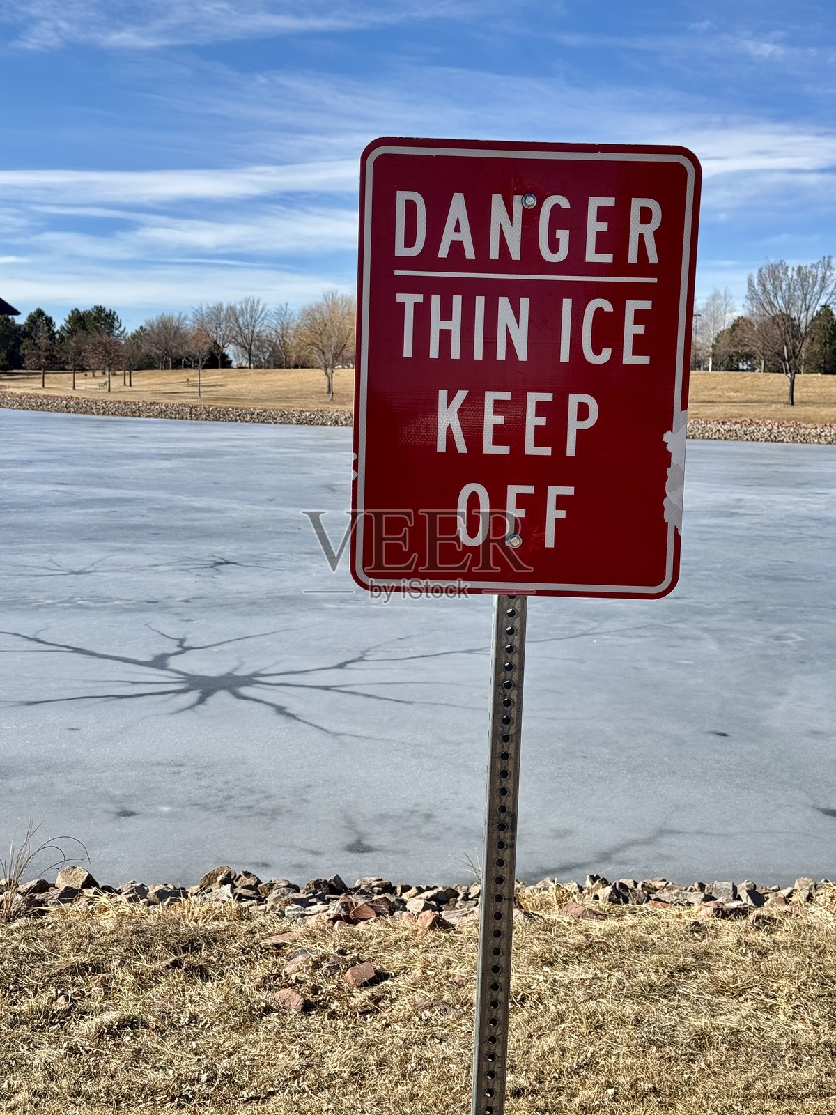 薄冰红色警告标志在裂开的池塘前照片摄影图片