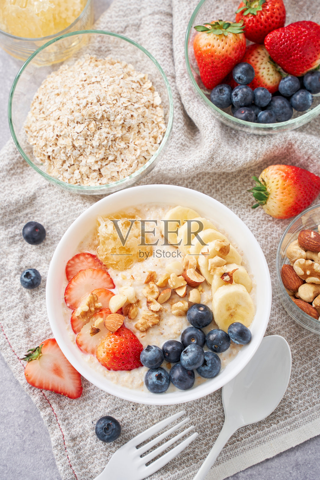 健康的燕麦早餐 – 配有水果、坚果和蜂蜜comb照片摄影图片