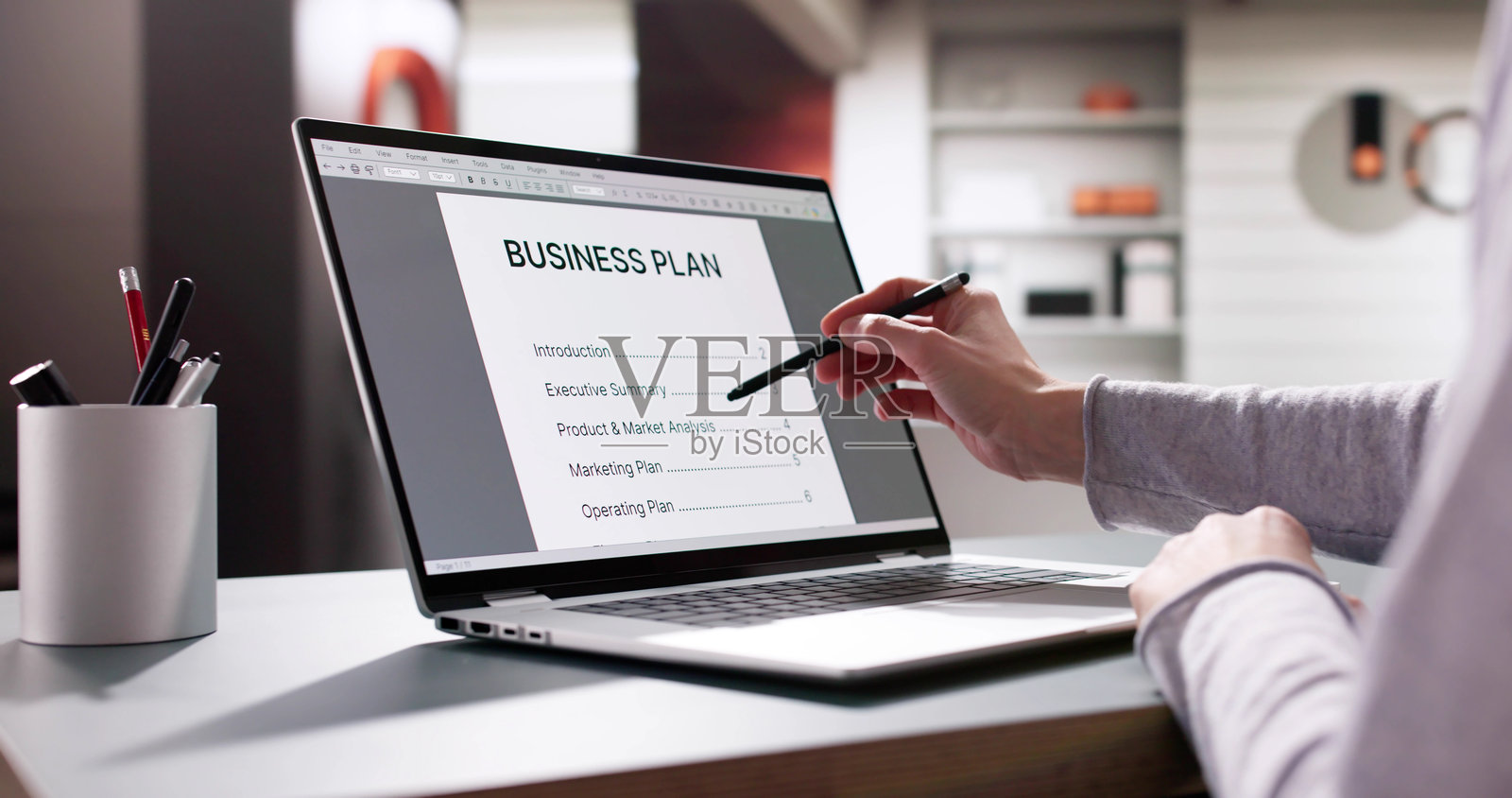 企业家在笔记本电脑上撰写商业计划,旁边有愿景文件照片摄影图片