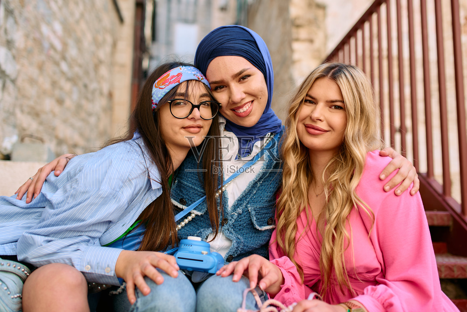 一群不同肤色的女性坐在历史悠久的老城阶梯上,愉快地探索并捕捉这个迷人旅游目的地的精髓。照片摄影图片