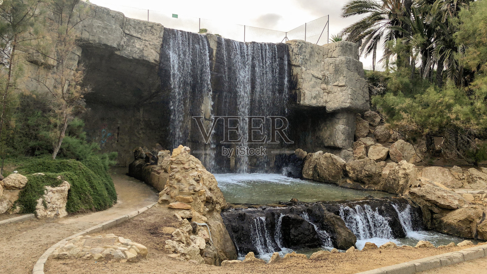 公园中人工瀑布流过岩石形成的景观照片摄影图片