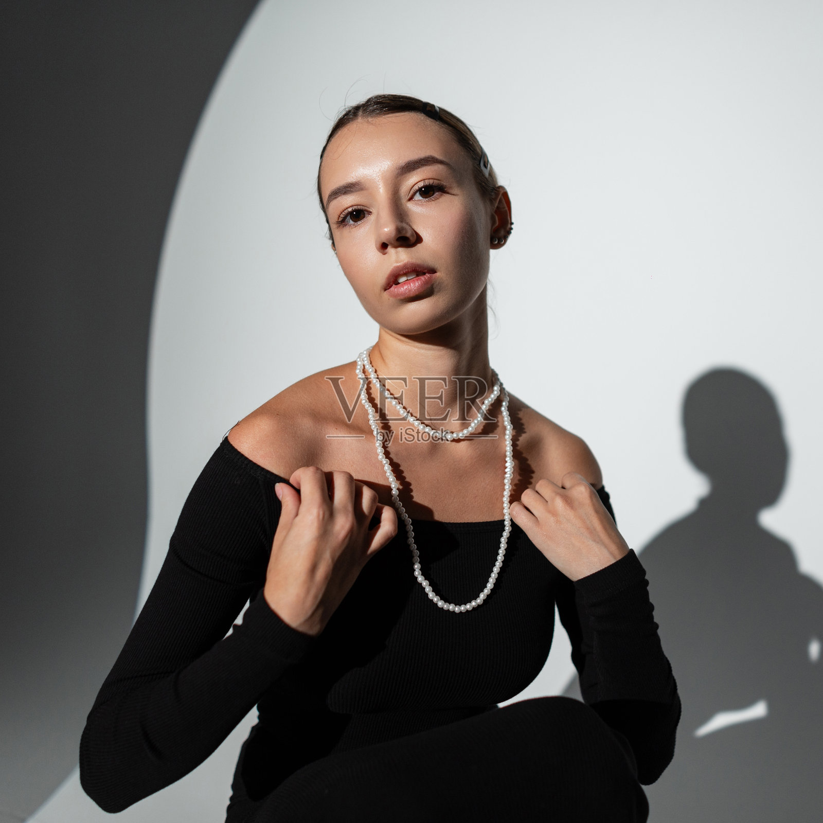 时尚优雅的美丽女孩穿着黑色时尚裙子,坐在暗背景的工作室中摆姿势。漂亮的女士照片摄影图片