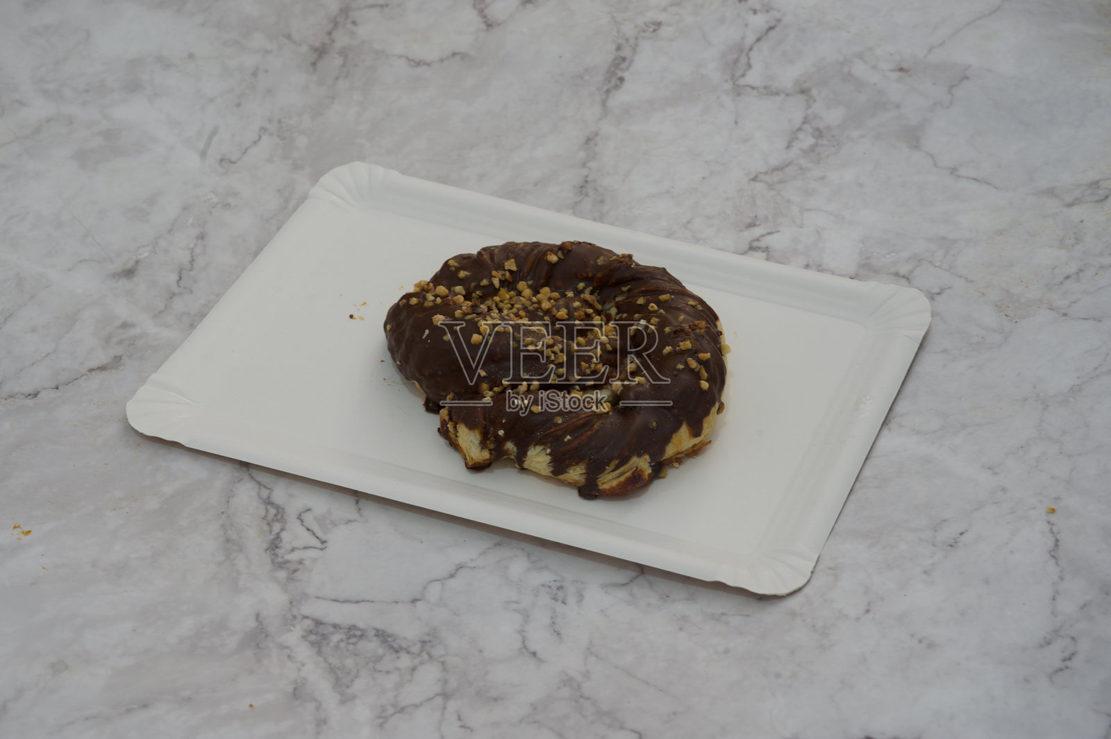 一块顶部撒有坚果的巧克力糕点放在白色盘子上照片摄影图片