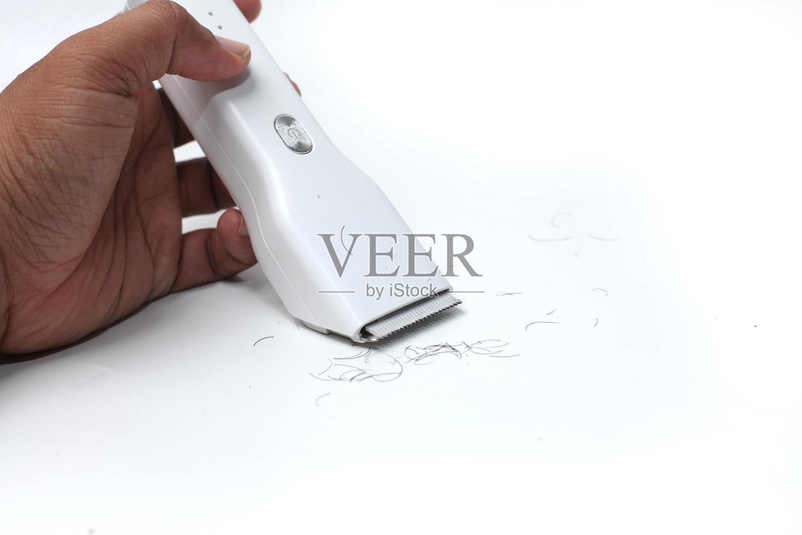 手持白色理发器,背景为白色。照片摄影图片