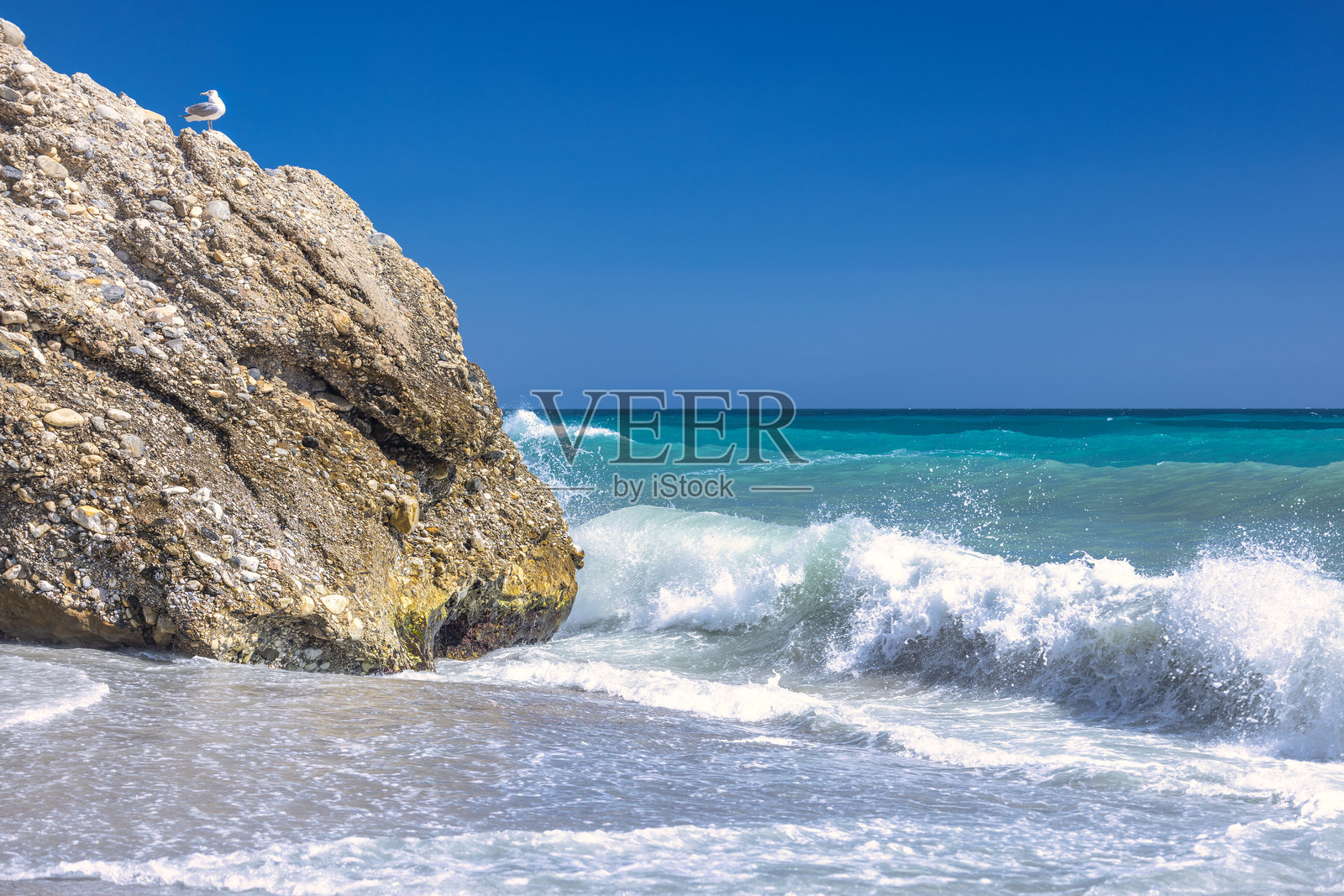 内尔哈镇,位于西班牙南部安达卢西亚的太阳海岸度假区。海浪拍打着岩石海岸,一只海鸥栖息在上面。照片摄影图片