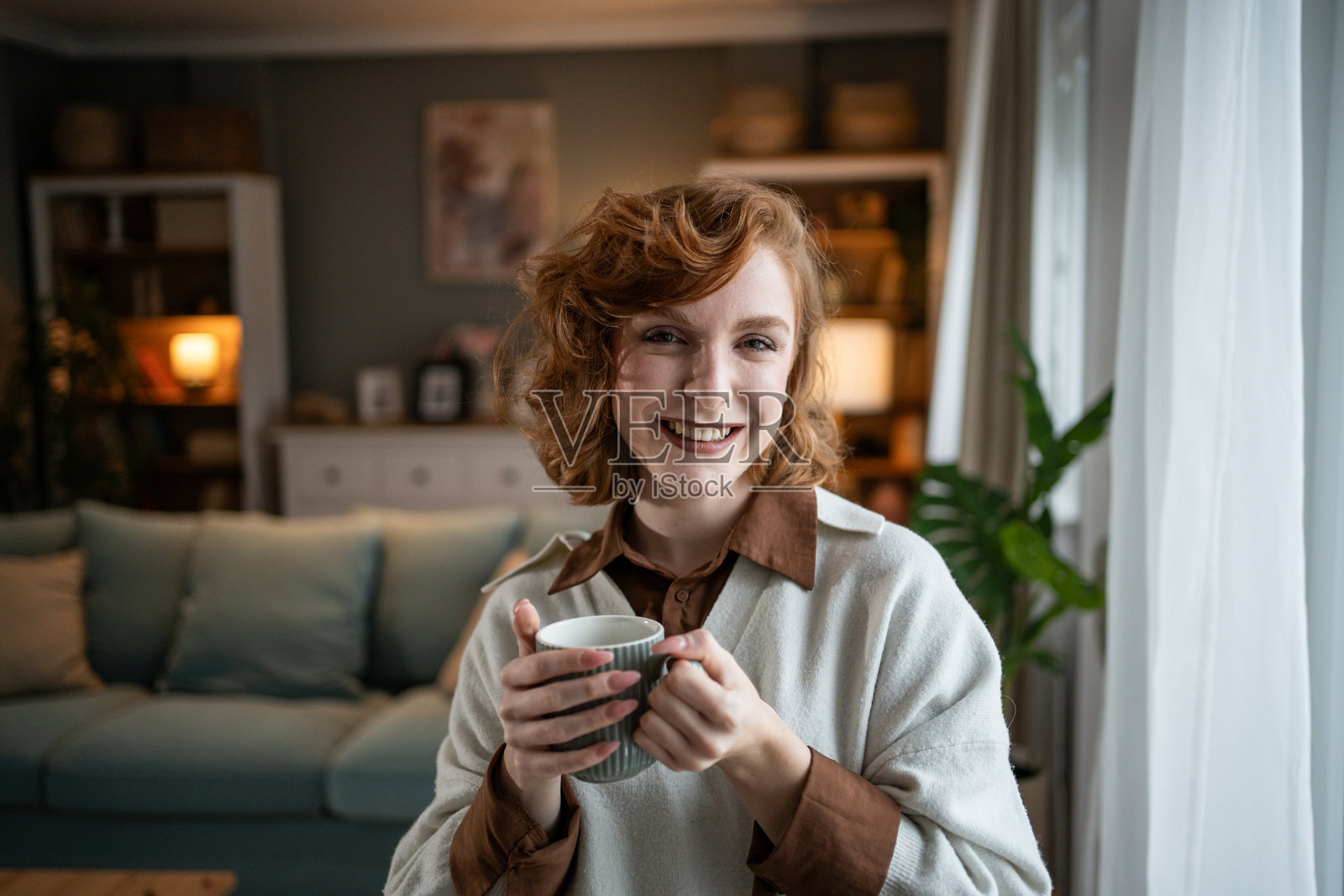微笑的年轻女性在家中手持杯子摆姿势照片摄影图片