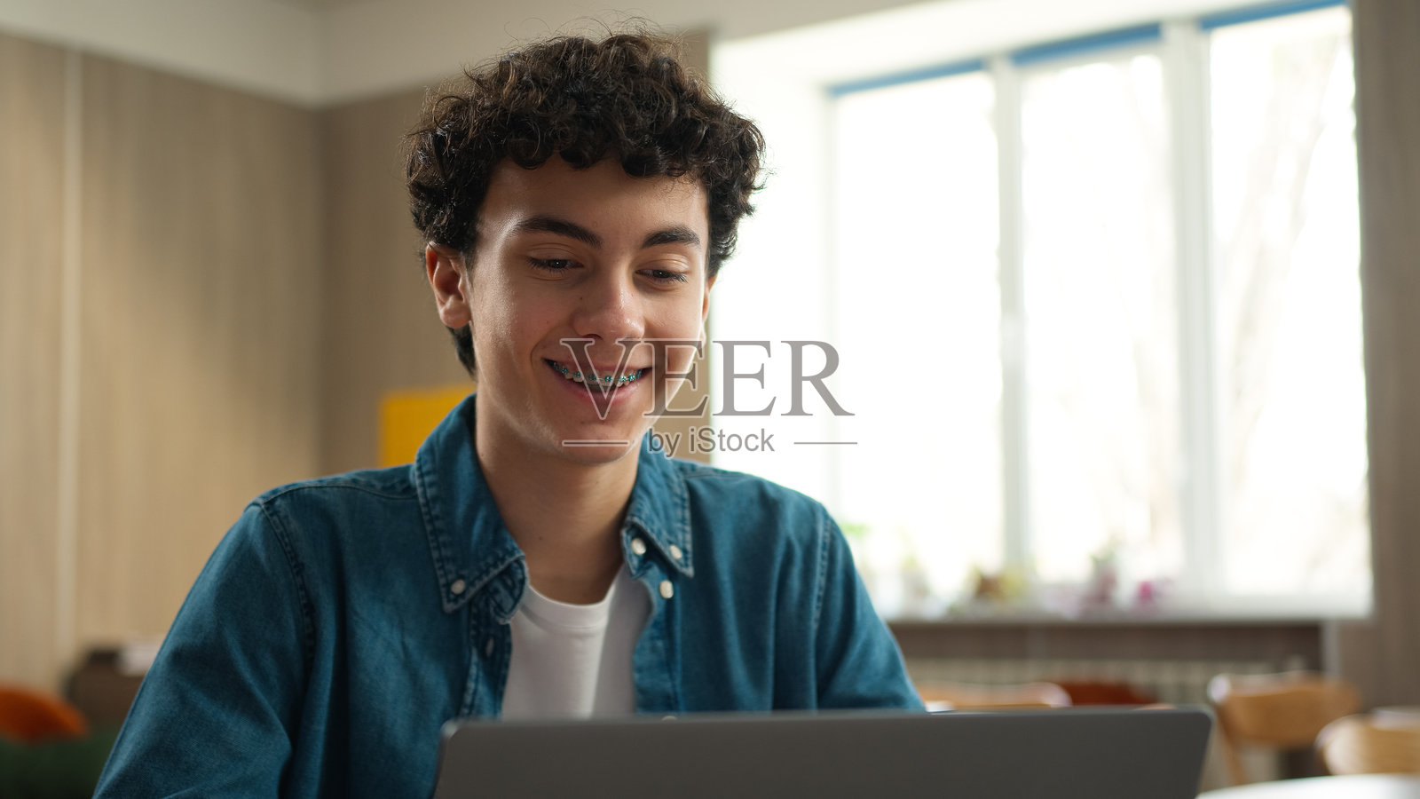 戴牙套的白人男学生在课堂上使用笔记本电脑学习在线知识照片摄影图片
