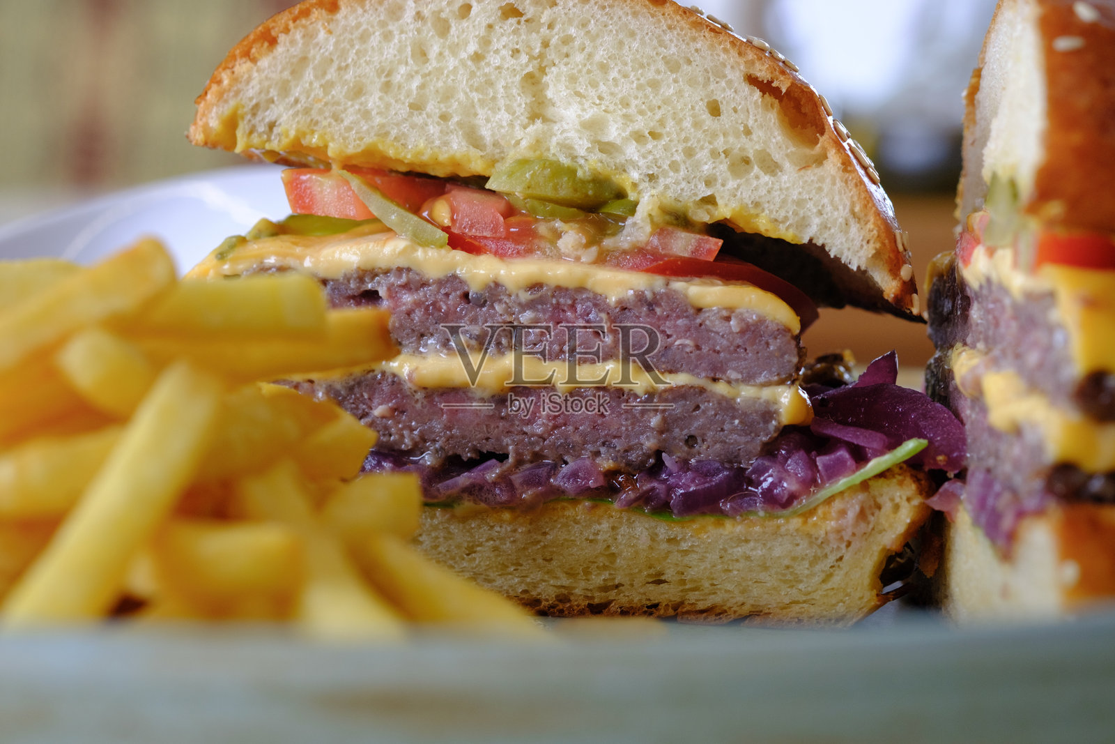 多汁的双层汉堡,配有融化的奶酪、新鲜的配料和酥脆的薯条照片摄影图片