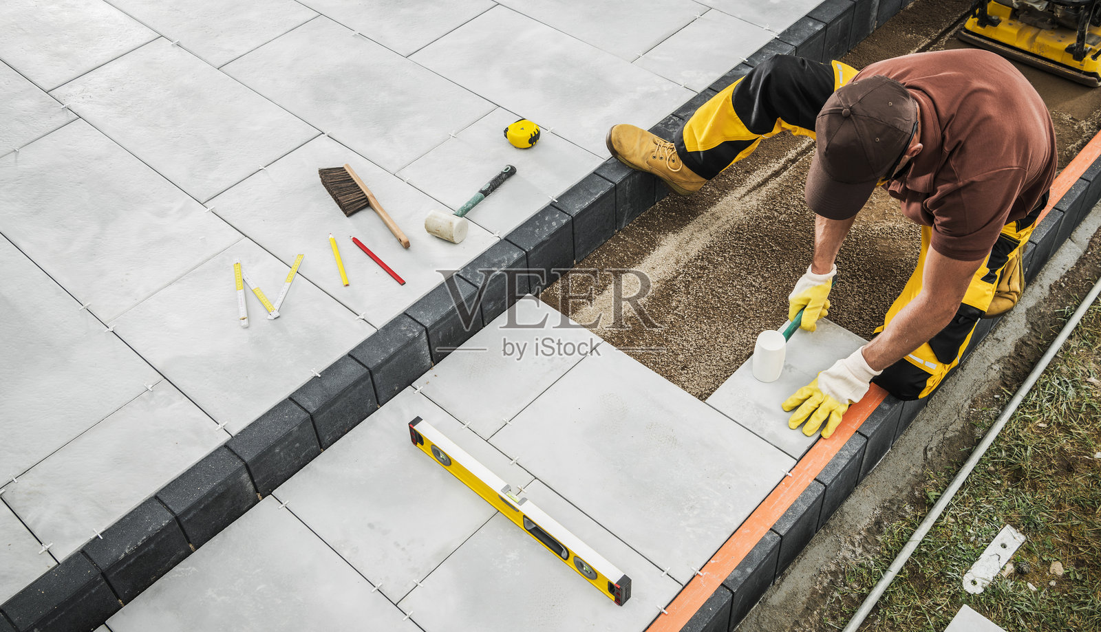 专业承包商在住宅后院铺设石砖,使用工具进行作业照片摄影图片