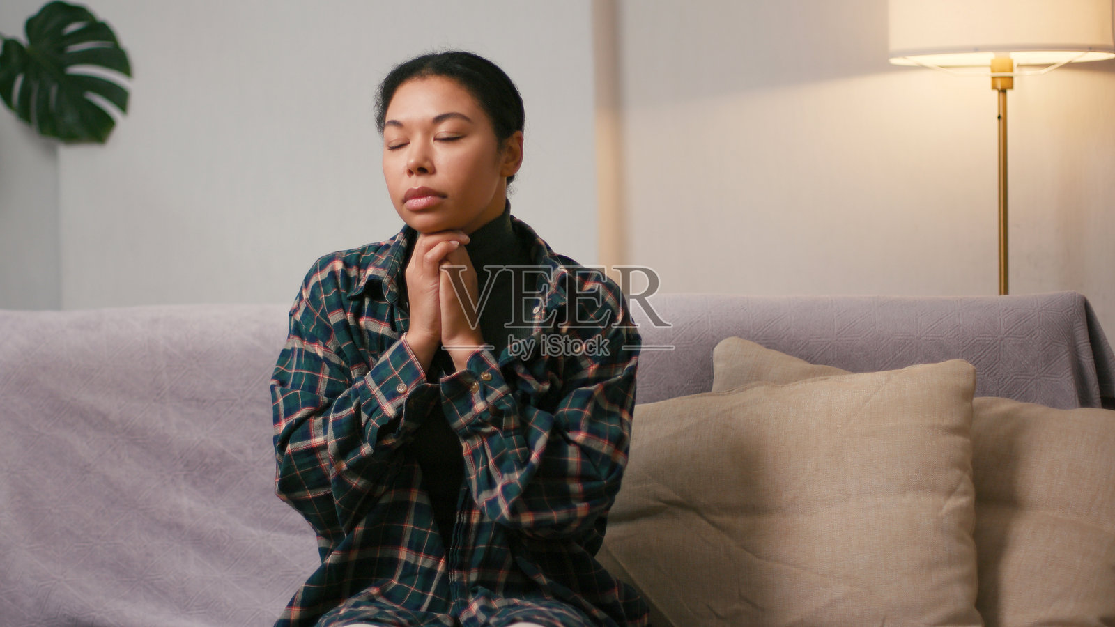 西班牙裔女性咬着嘴唇,双手合十祈祷。照片摄影图片