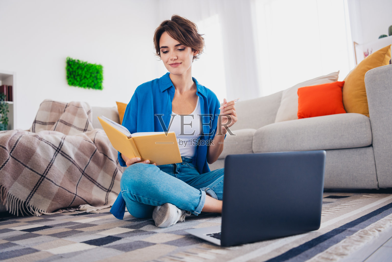 可爱的棕发女孩坐在宿舍地板上,听着居家学习的讲座。照片摄影图片